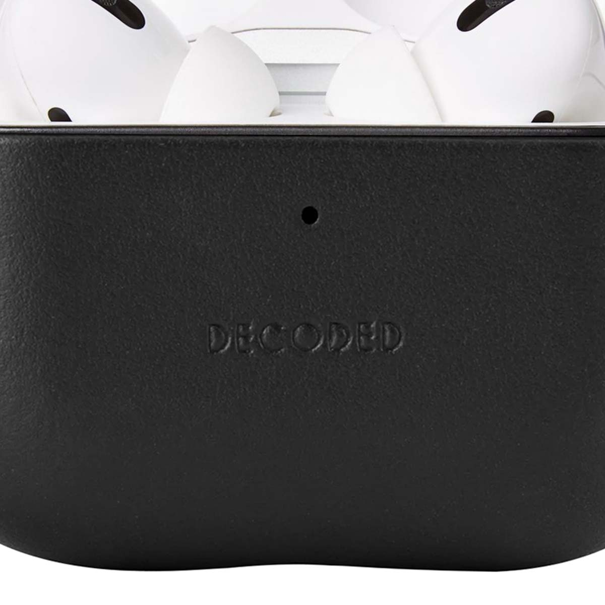 Primer plano de un estuche negro con 'DECODED' grabado. Se ven auriculares blancos arriba. El estuche tiene un pequeño punto.