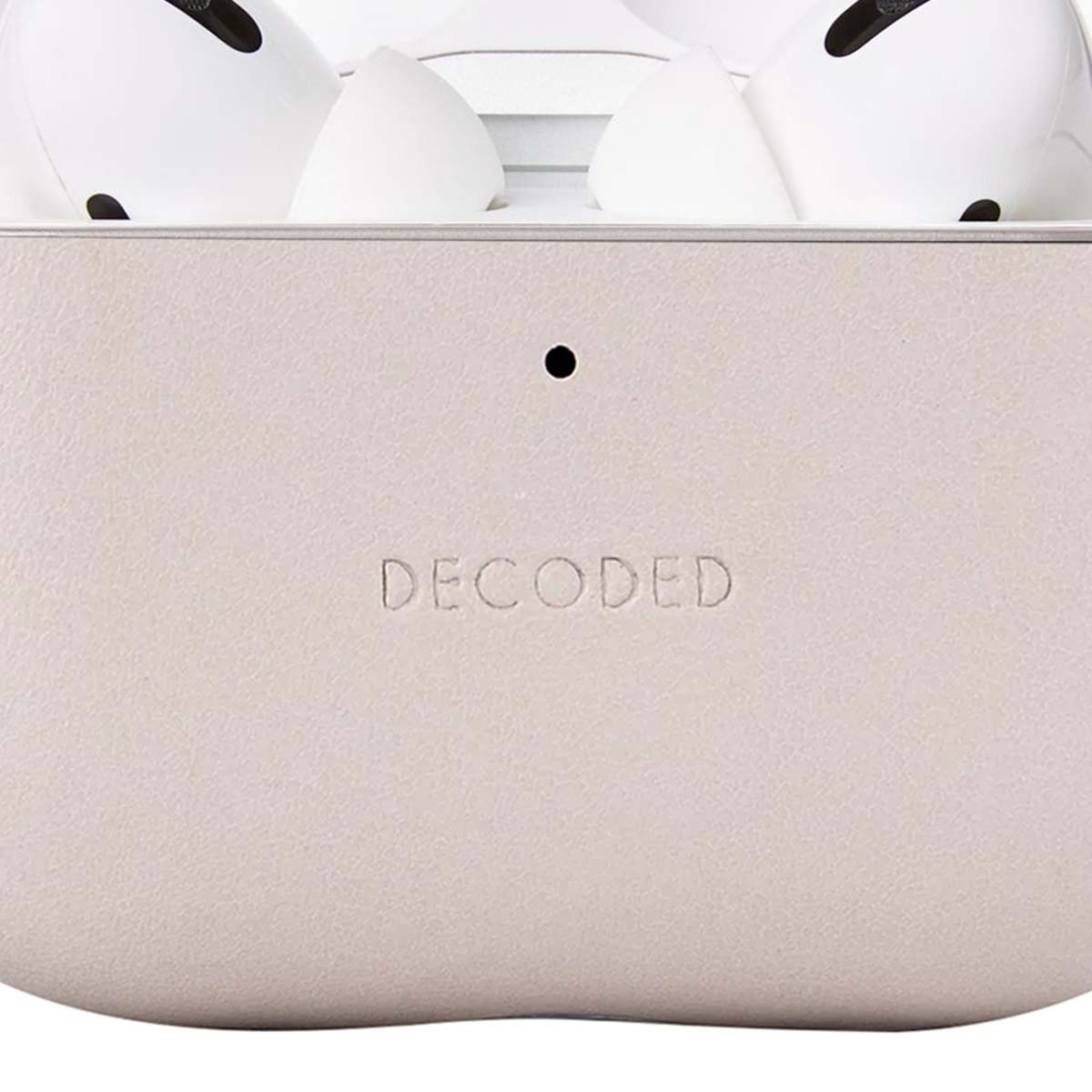 Primer plano de un estuche beige claro con la palabra 'DECODED' en relieve. Arriba, auriculares blancos.