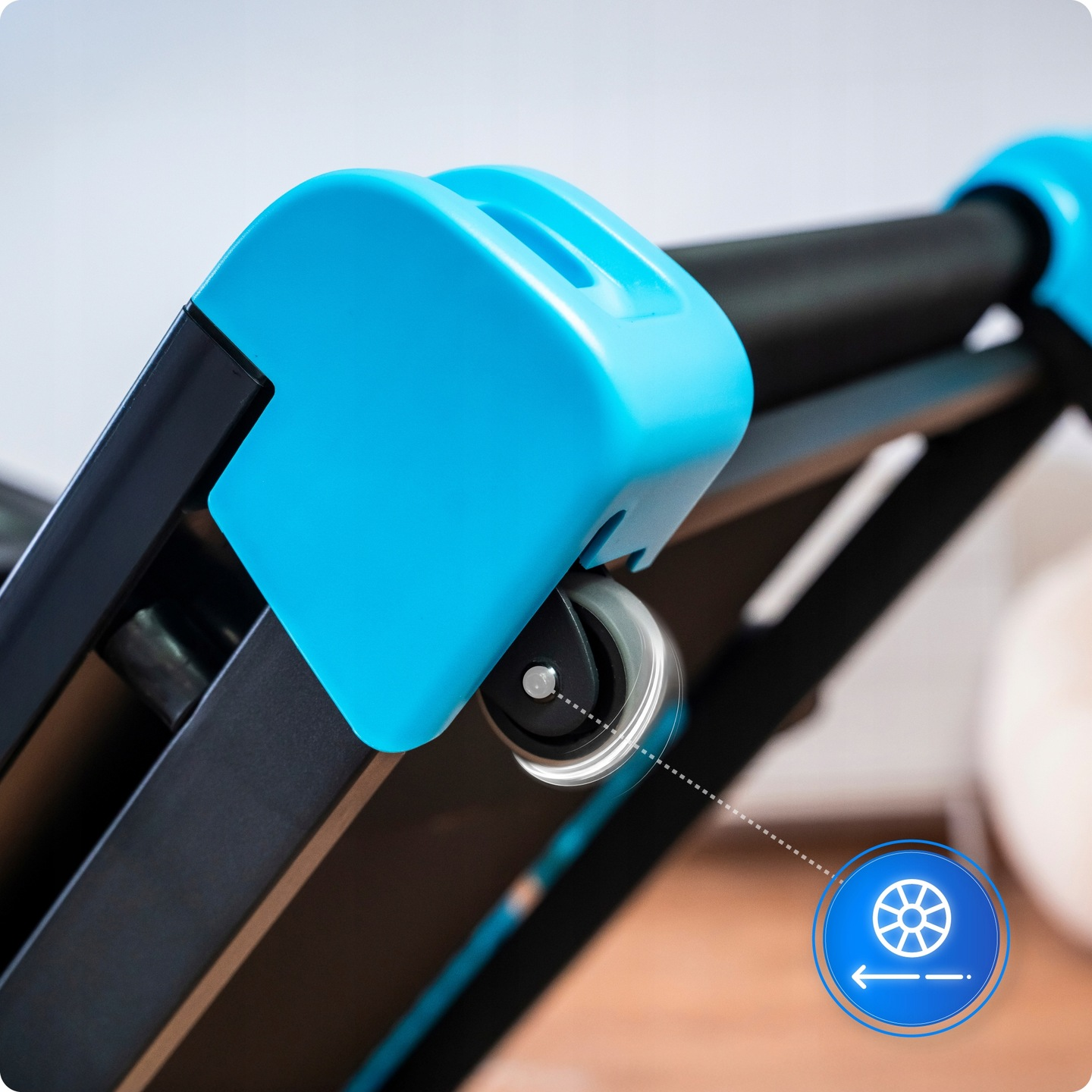 Zbliżenie niebiesko-czarnej maszyny do ćwiczeń z kołem i ikoną pokazującą kierunek ruchu koła.