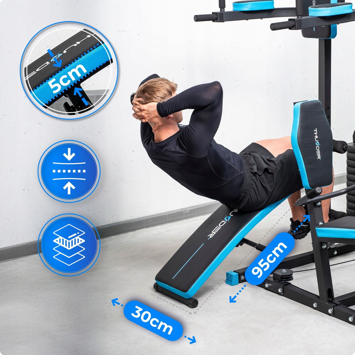 Mężczyzna ćwiczy na niebiesko-czarnej ławce do ćwiczeń. Robi brzuszki. Wymiary są podświetlone na zdjęciu.
