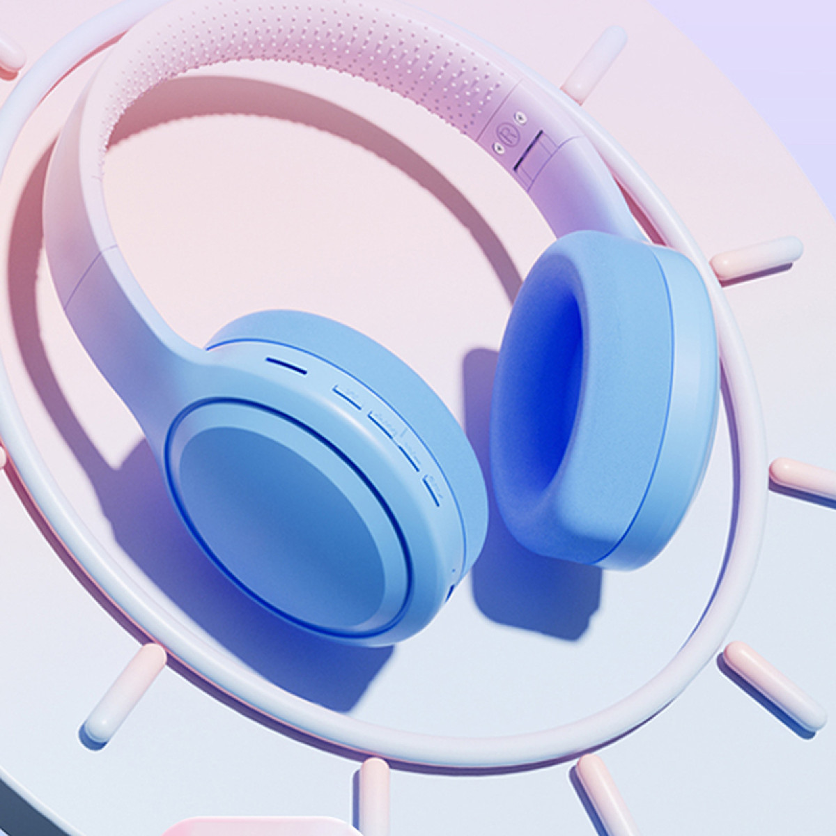 Blaue Kopfhörer mit rosa Kopfband liegen auf einer weißen und rosa kreisförmigen Struktur, umgeben von rosa Stäben.