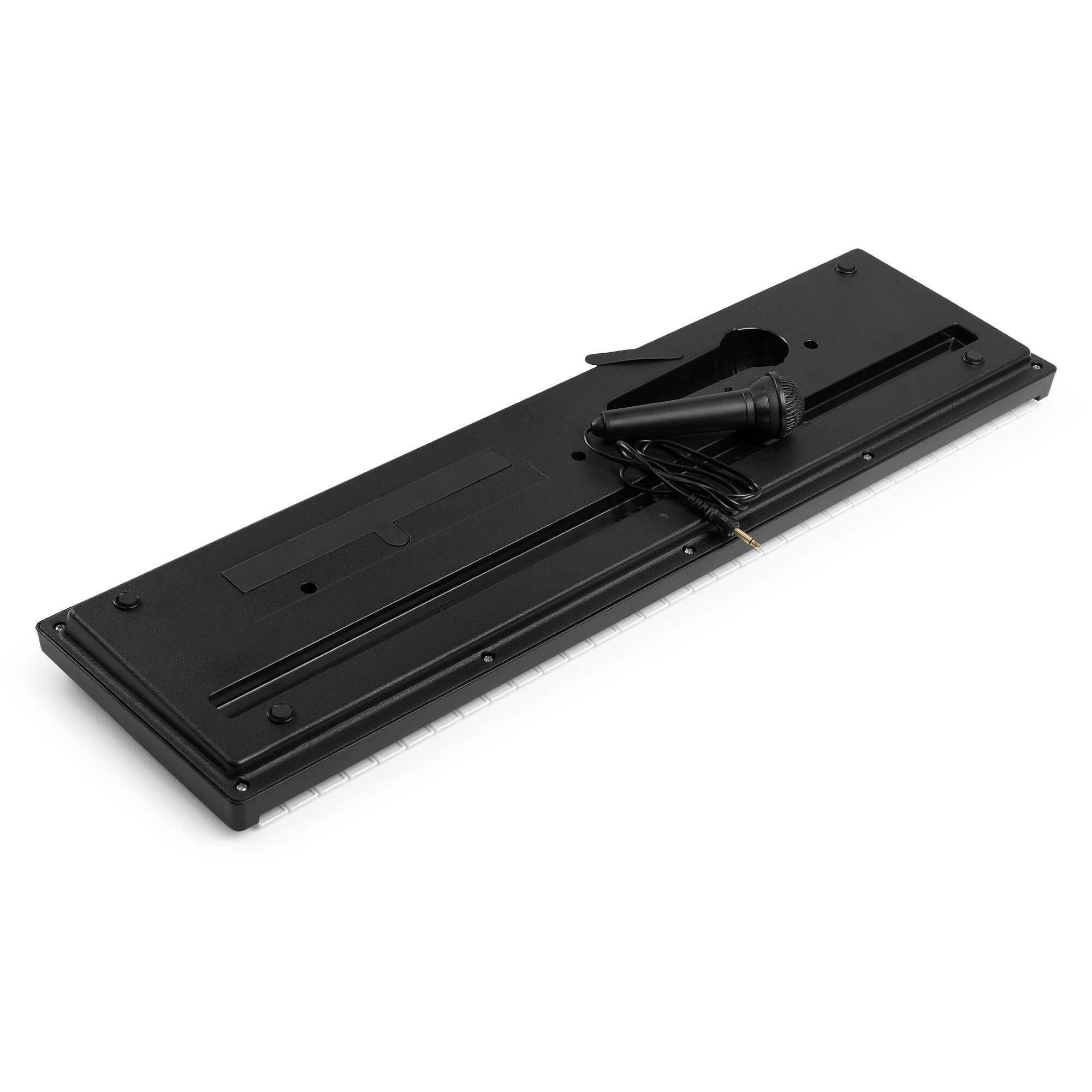Teclado de juguete negro con micrófono sobre fondo blanco. Las teclas son blancas y negras.