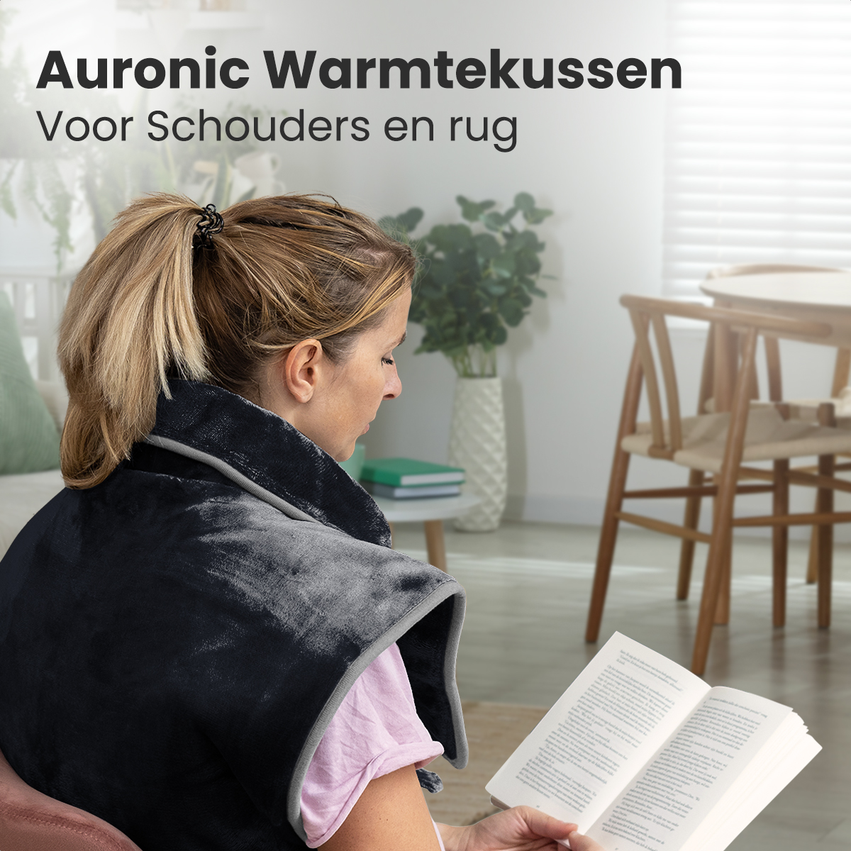 Woman with a black heating pad reading a book. Text on top says 'Auroinc Warmtekussen'.
