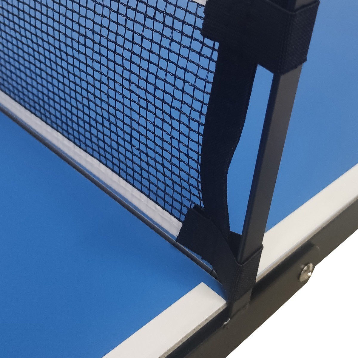 A close-up of a ping pong table net. The net is black mesh, set against a blue table and a white frame, with a blue sky.