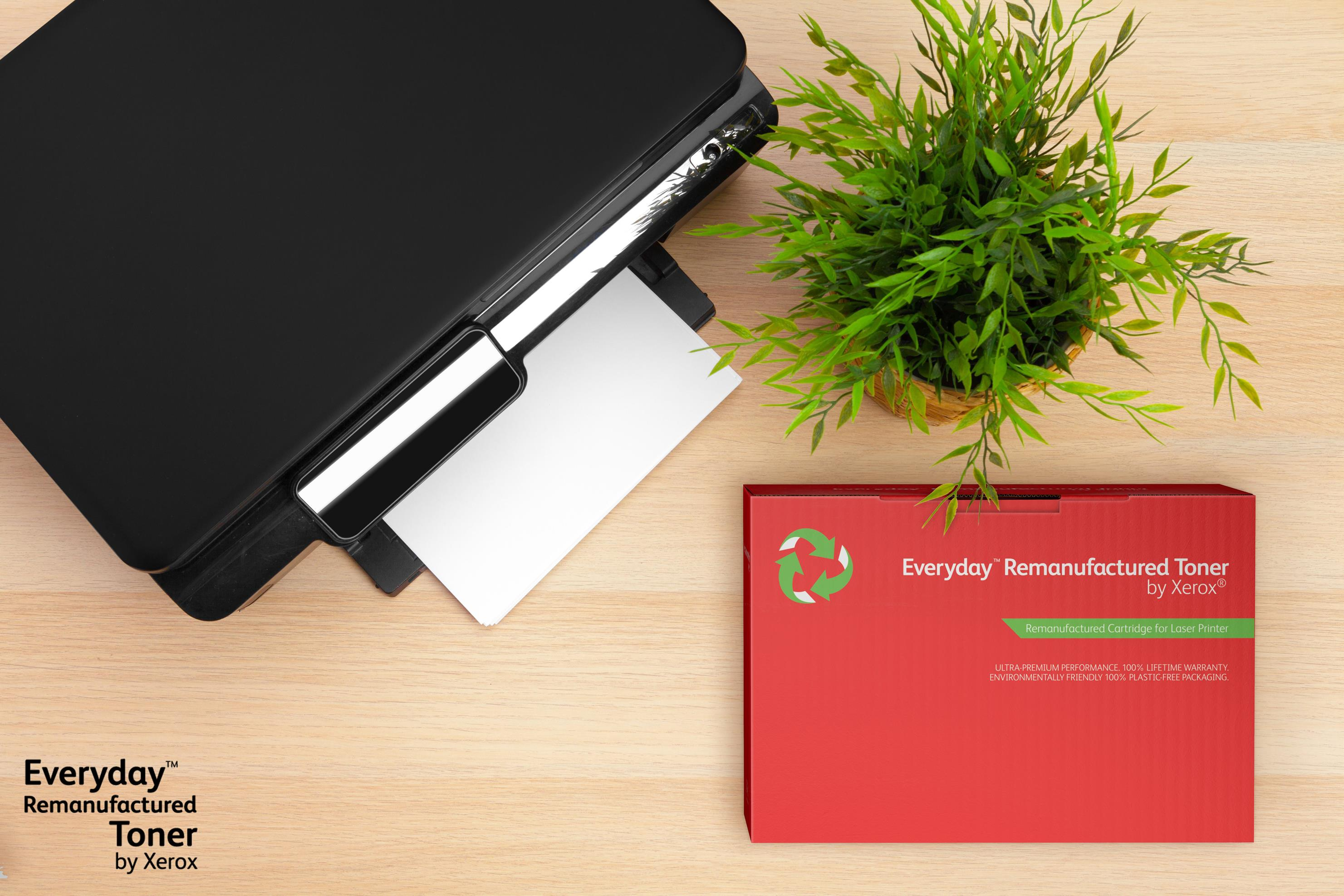 Drukarka i kartridż z tonerem na drewnianej powierzchni. Po prawej roślina. Pudełko jest czerwone.