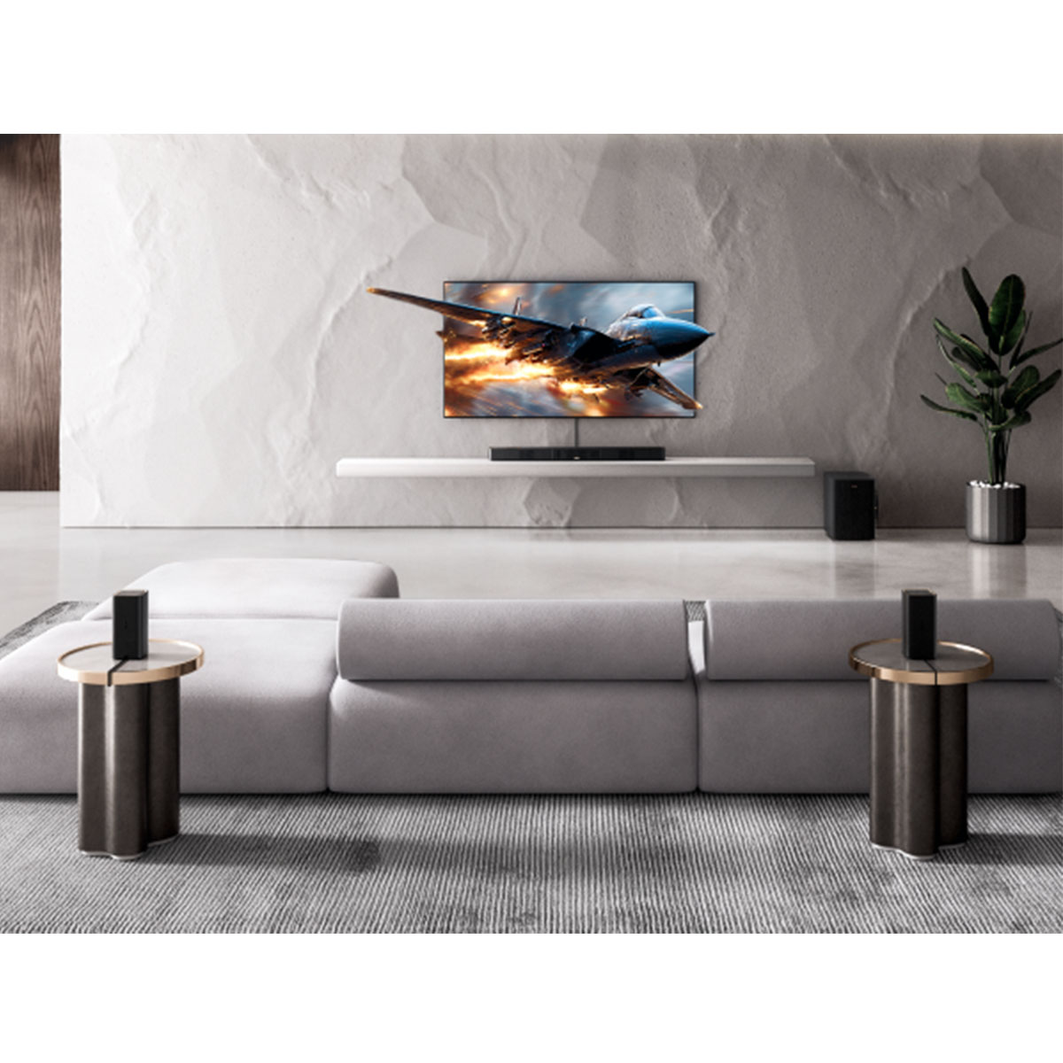 Nowoczesny salon z dużym telewizorem pokazującym odrzutowiec. Jest szara sofa, dwa stoliki i roślina.