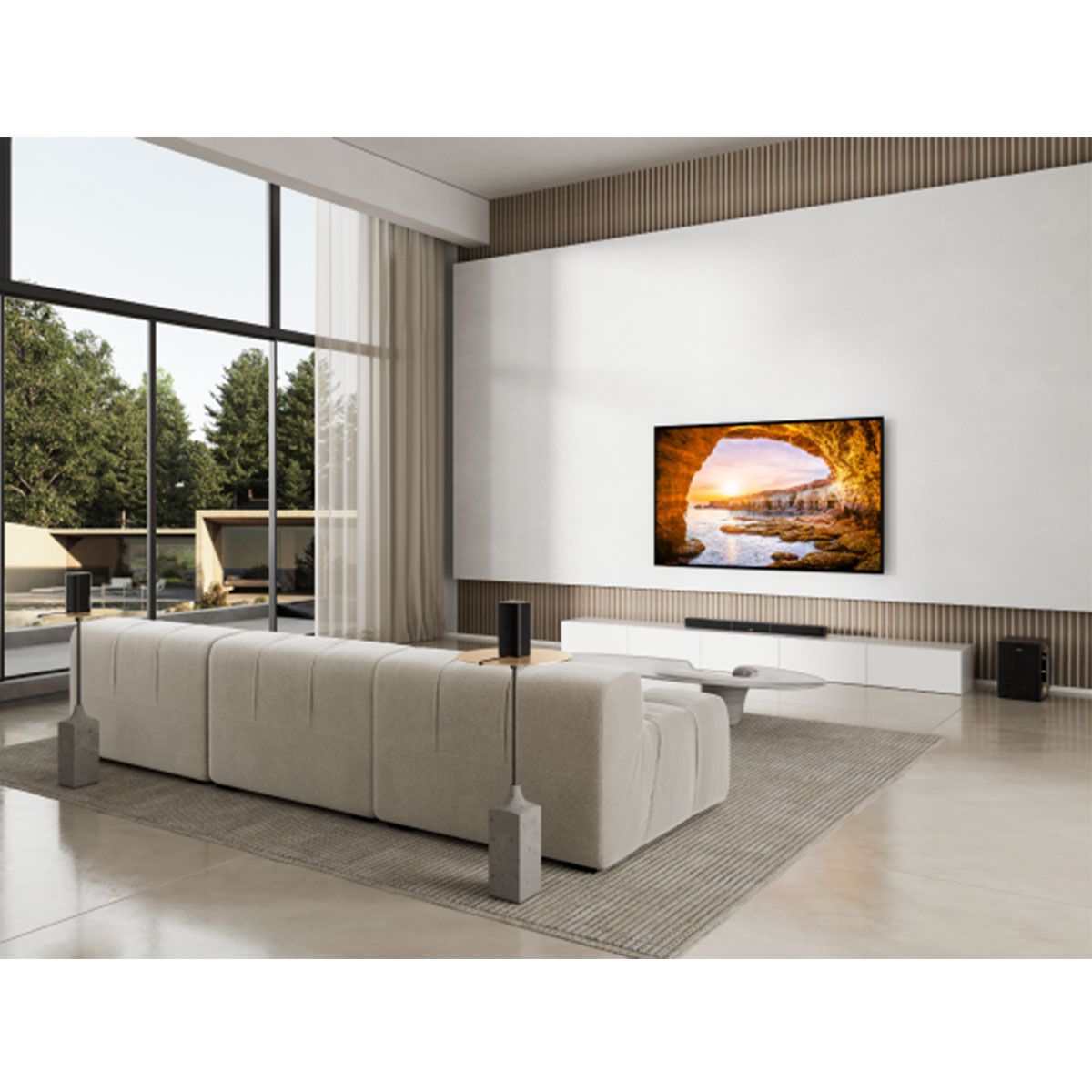 Salon z dużym telewizorem pokazującym zachód słońca, jasną sofą i dużymi oknami z widokiem.