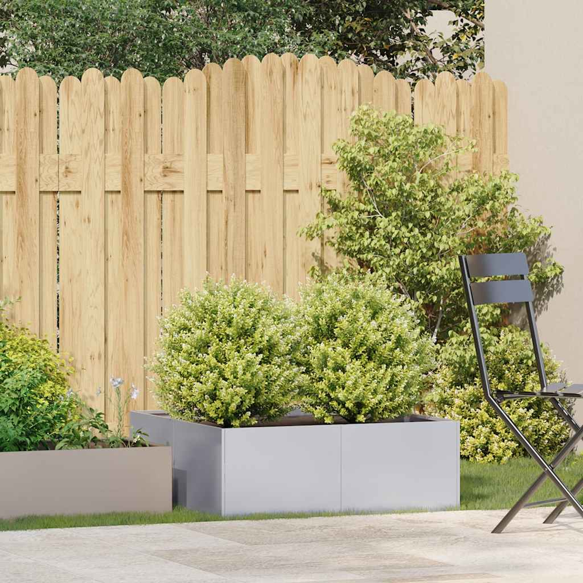 Una scena di giardino con una staccionata in legno, cespugli verdi, una sedia in metallo e fioriere. Il terreno è pavimentato, con erba e piante.