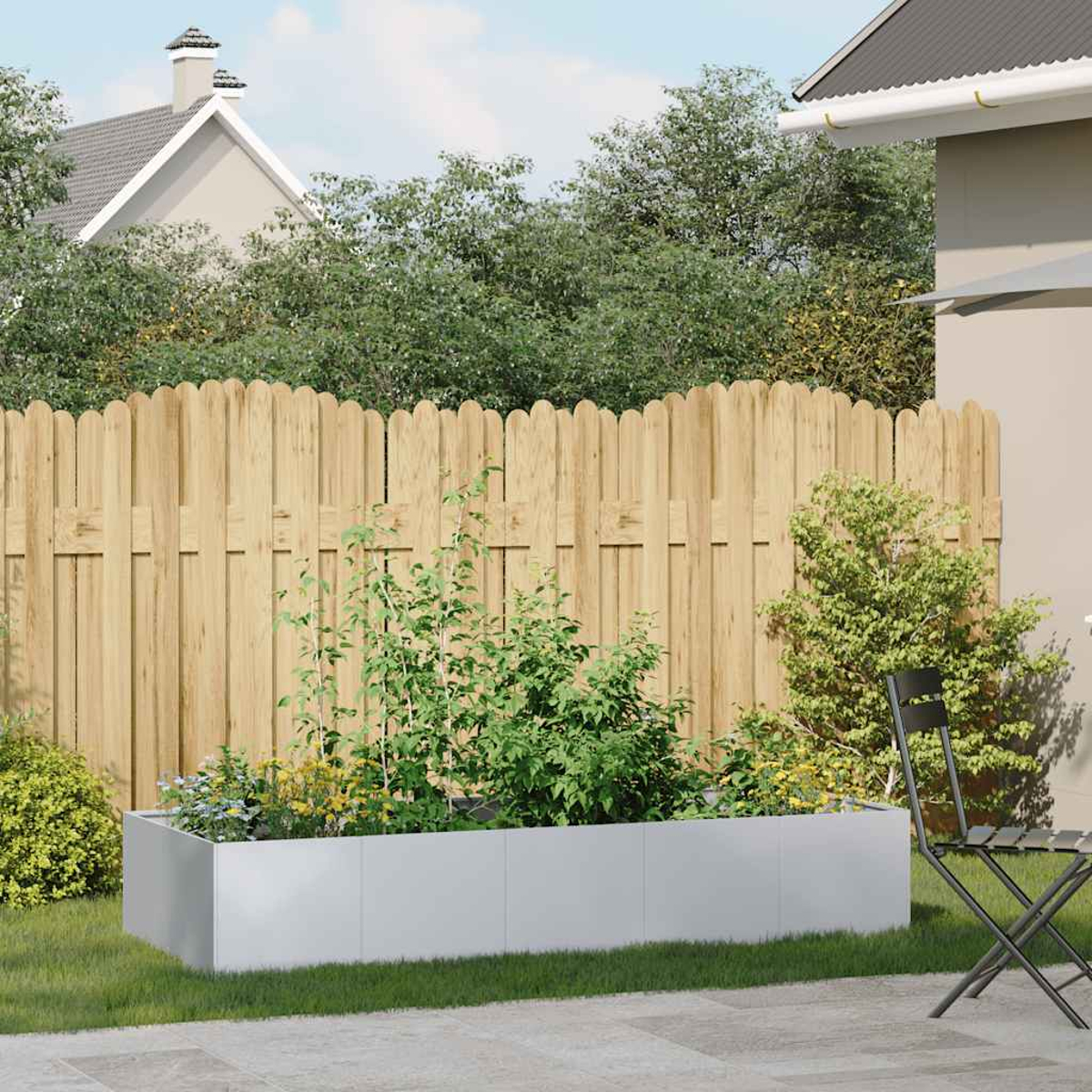 Un giardino con una fioriera in metallo piena di piante. Una recinzione di legno e case sullo sfondo. Una sedia a destra.