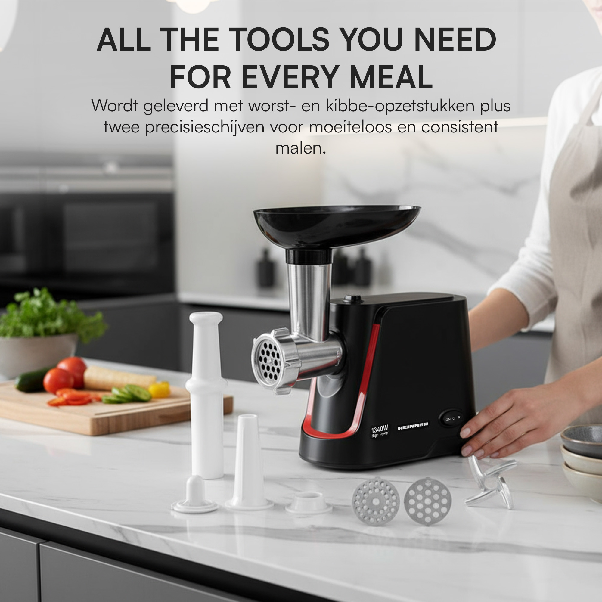 A meat grinder with accessories on a counter, with ingredients and a person's hand in the scene.