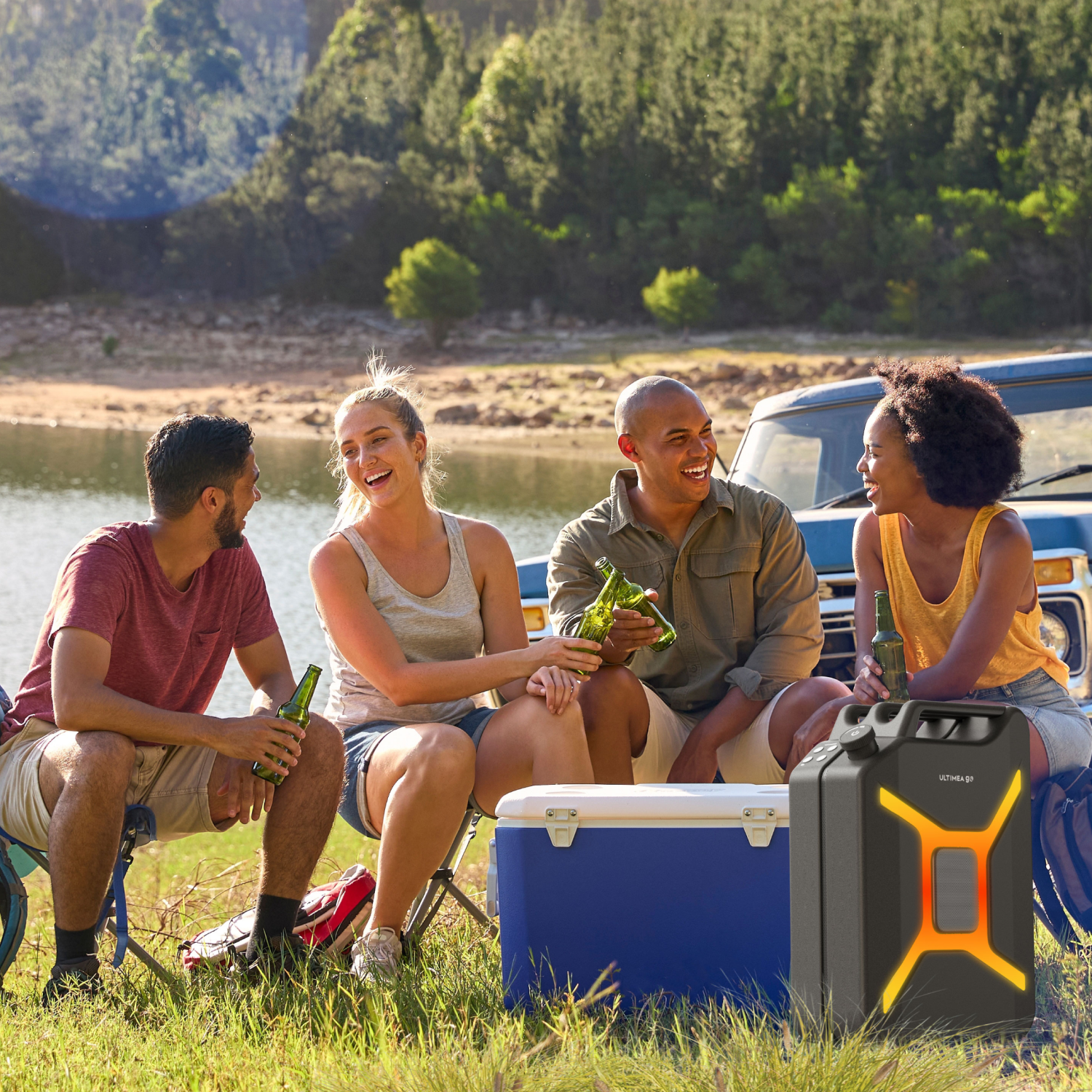 Vier Freunde bei einem Picknick am See, die Bierflaschen halten und lachen. Ein blauer Kühler, Lautsprecher und ein Oldtimer-Truck sind ebenfalls vorhanden.