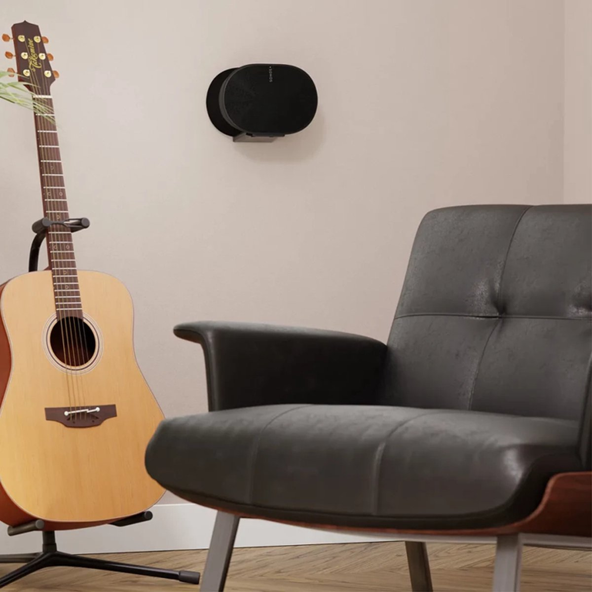 Akoestische gitaar op een standaard, zwarte stoel en een zwarte luidspreker aan de muur. Een serene binnenomgeving.