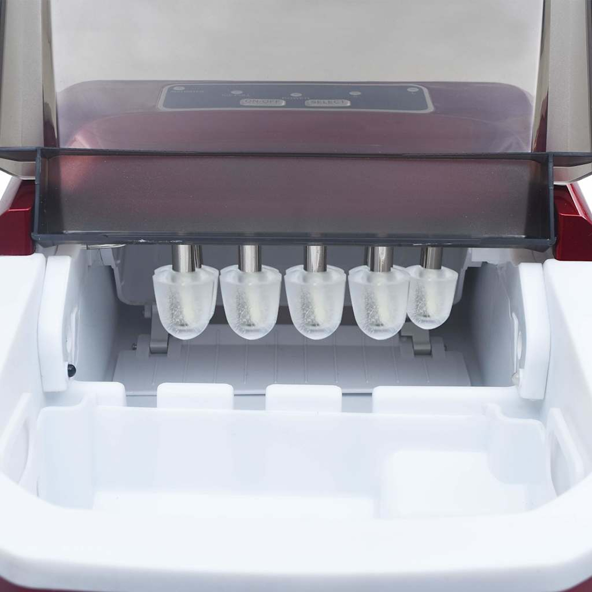 Una máquina de hacer hielo, abierta. Tiene moldes de hielo transparentes colgando. La máquina es mayormente blanca y roja.