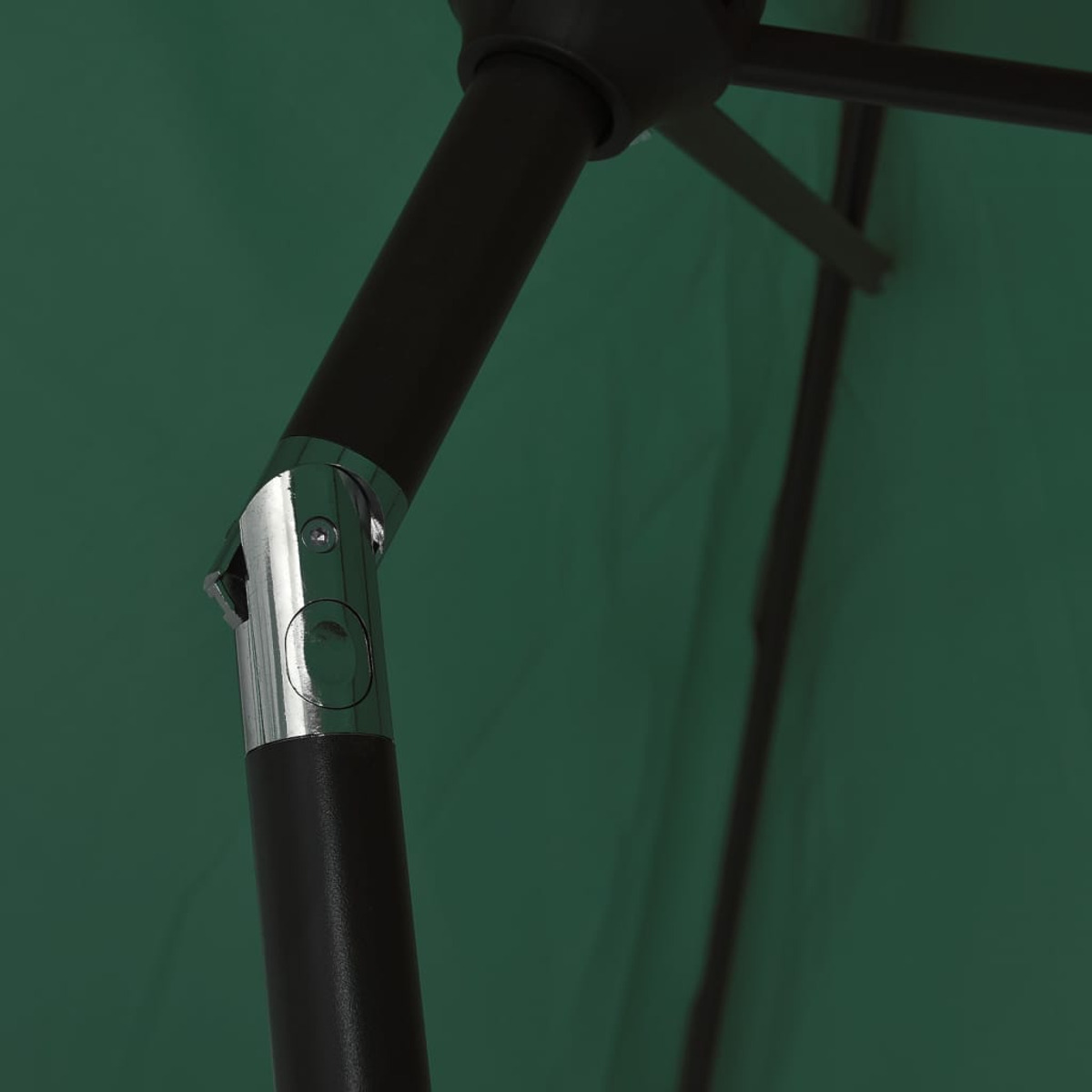 Primo piano di un ombrello verde. Sono visibili un palo marrone scuro e un giunto metallico. Lo sfondo è un tessuto verde.