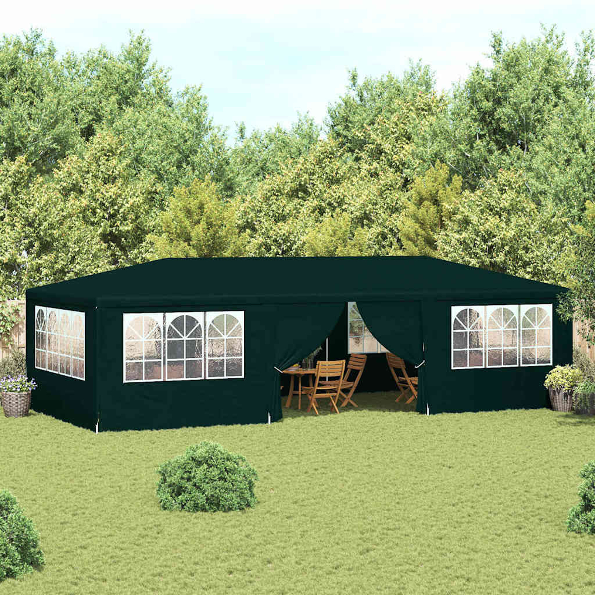 Una tenda verde scuro con finestre con cornice bianca è posizionata su un prato. Alberi sullo sfondo, un tavolo e sedie all'interno.