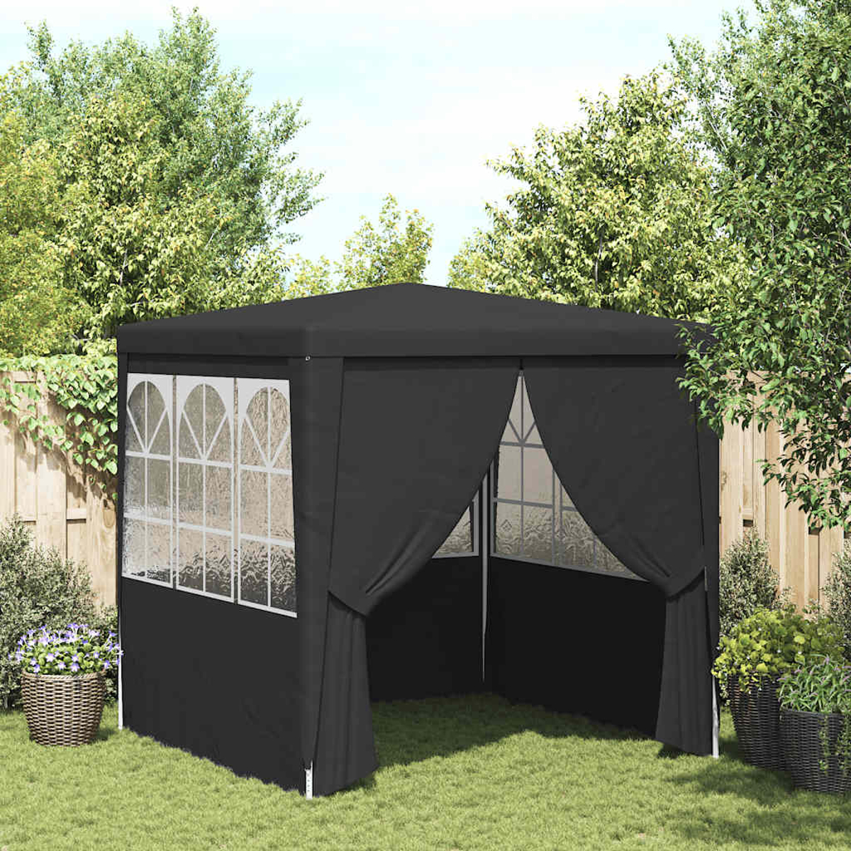 Un gazebo nero in un giardino. Ha finestre con cornice bianca, tende ed è circondato da alberi, erba e una recinzione di legno.