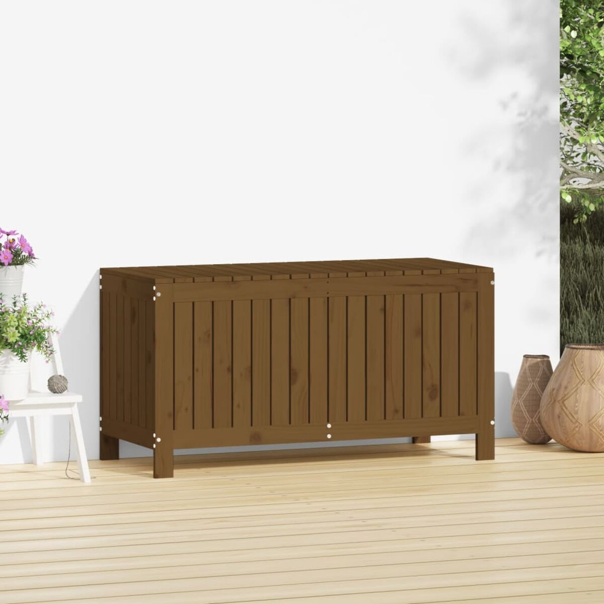 Un baule di legno marrone su un ponte di legno. Un muro bianco dietro, con piante e vasi ai lati.