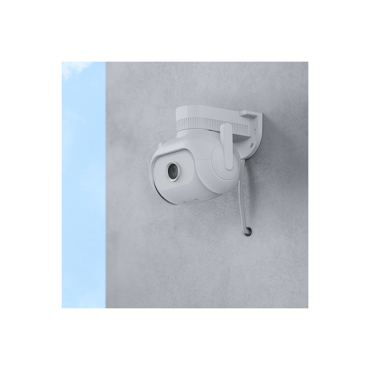 Biała kamera bezpieczeństwa zamontowana na szarej ścianie. Na tle widoczne jest niebo.