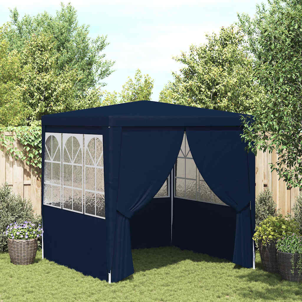 Un gazebo blu navy in un giardino. Ha finestre con cornice bianca, tende aperte ed è circondato da alberi e piante.