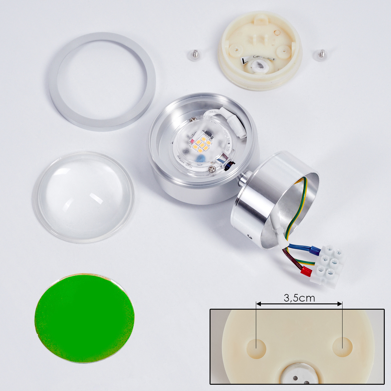 Zerlegte LED-Lichtkomponenten. Enthält Linse, Ring und Basis. Drähte und ein grüner Aufkleber sind ebenfalls vorhanden. Ein 3,5 cm langer Abschnitt ist hervorgehoben.