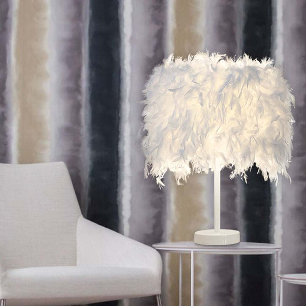 Eine weiße Federlampe auf einem kleinen Tisch, ein weißer Stuhl links und gestreifter Hintergrund.