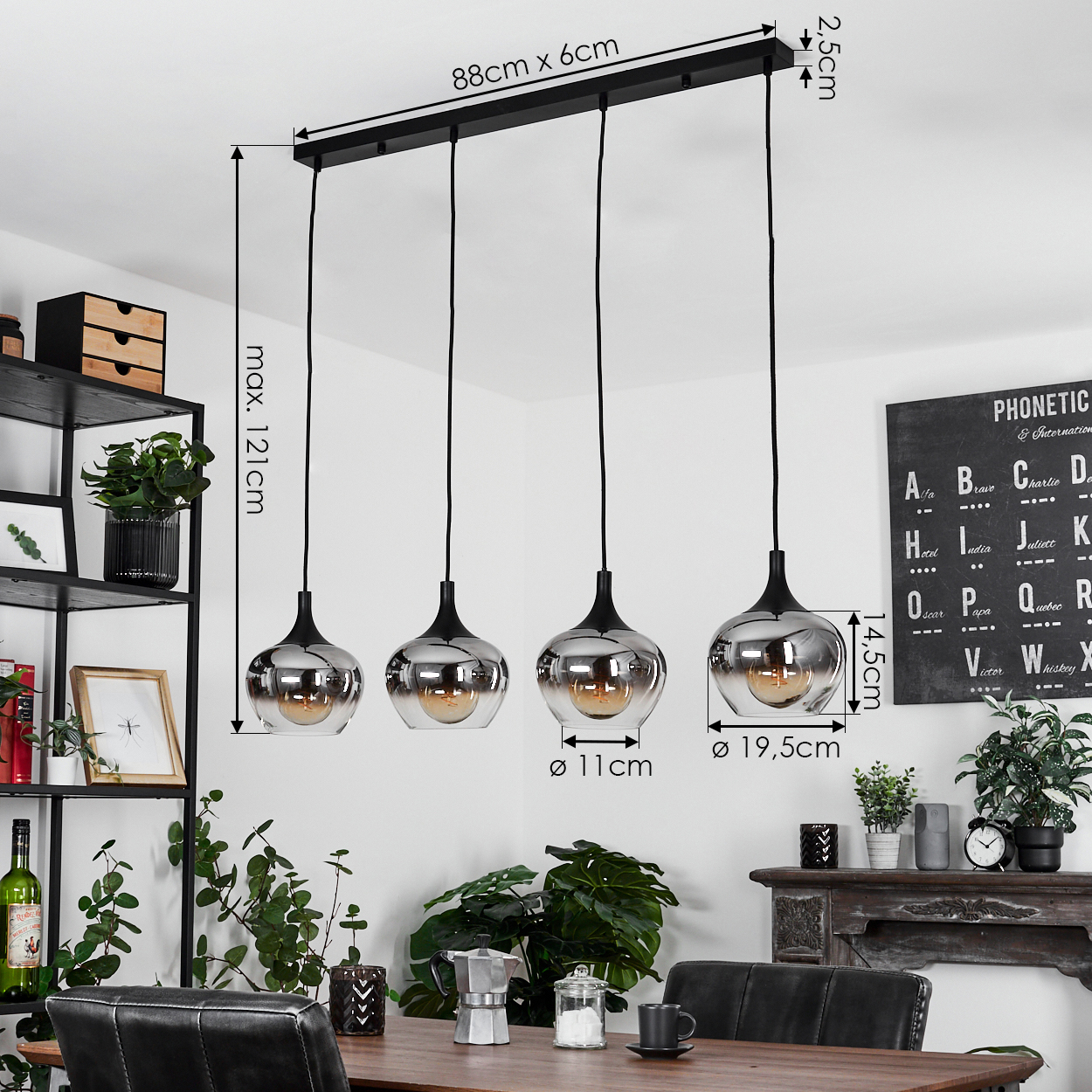 Vier Pendelleuchten hängen über einem Esstisch. Jede hat einen silbergrauen Glasschirm und ein schwarzes Kabel. Pflanzen und ein schwarzes Regal sind sichtbar.