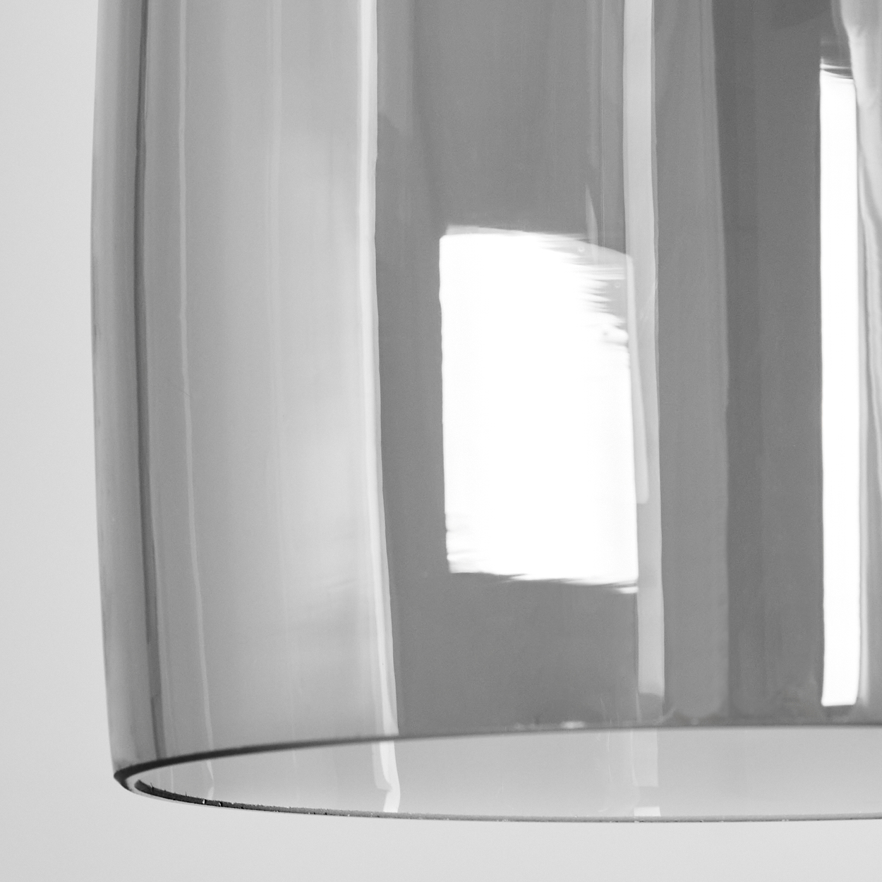 Nahaufnahme eines transparenten, zylindrischen Objekts, wahrscheinlich Glas. Es reflektiert Licht, mit vertikalen Linien und einem hellen, rechteckigen Highlight.