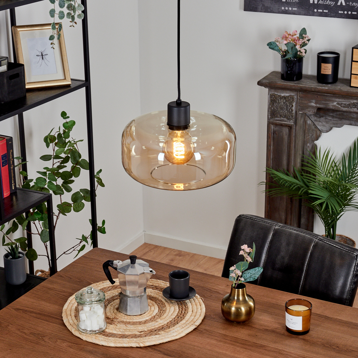 Ein Esszimmer mit einem Tisch, der für Kaffee gedeckt ist. Eine Hängelampe beleuchtet den Tisch. Eine Kaffeemaschine steht auf dem Tisch.
