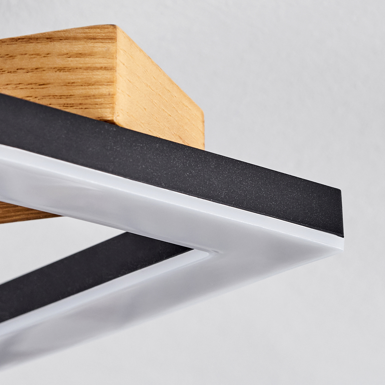 Nahaufnahme einer modernen Lampe. Sie hat einen Holzblock und ein rechteckiges Licht mit schwarzen und weißen Teilen vor weißem Hintergrund.