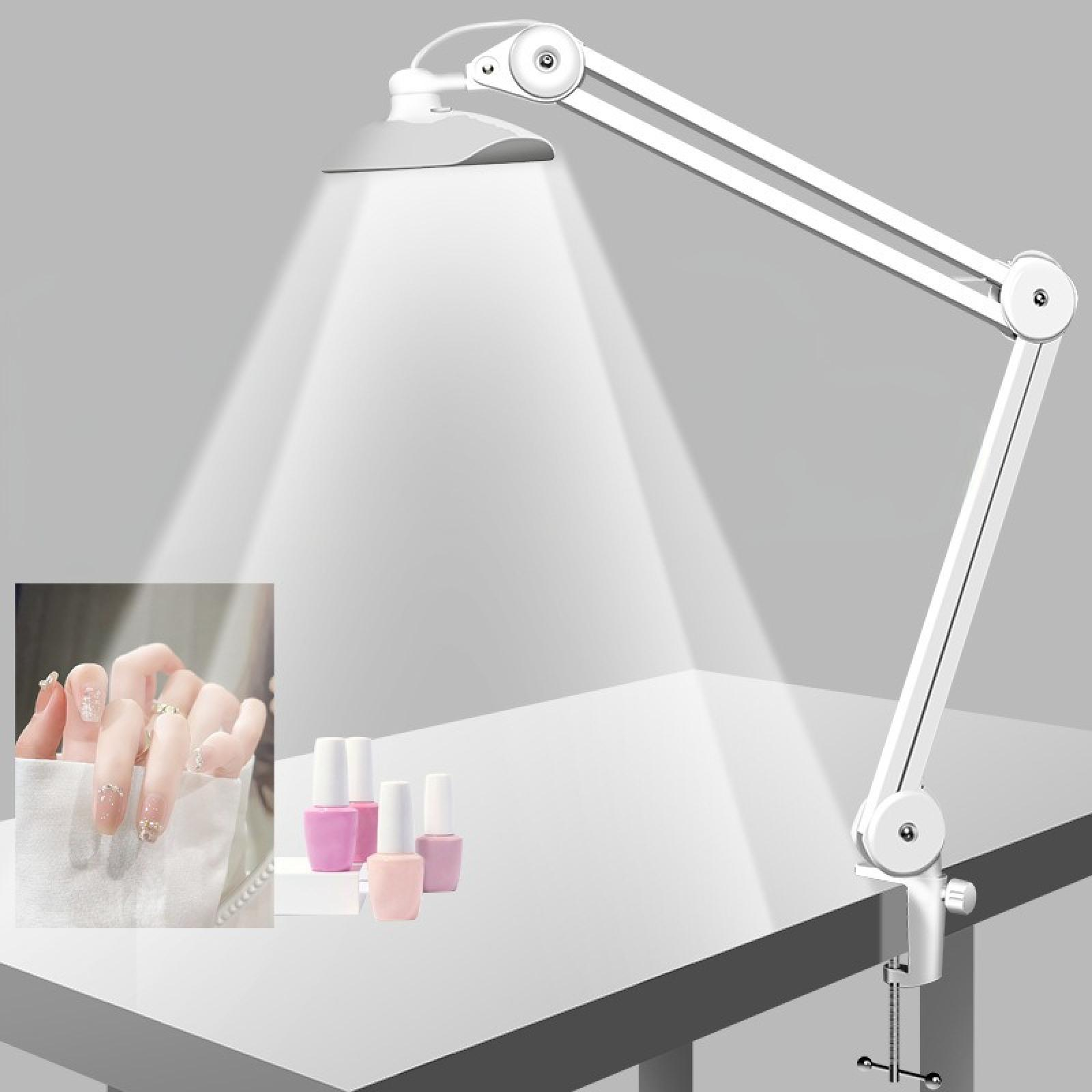 Weiße Schreibtischlampe beleuchtet einen Tisch. Nagellackflaschen und eine manikürte Hand liegen auf dem Tisch. Grauer Hintergrund.