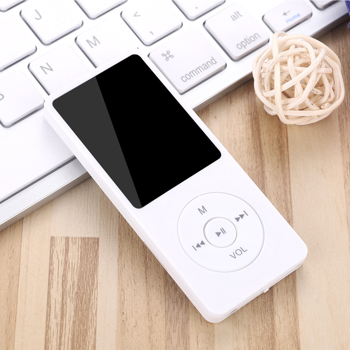 Weißer MP3-Player mit schwarzem Bildschirm auf Holzoberfläche, neben Tastatur und Dekokugel.