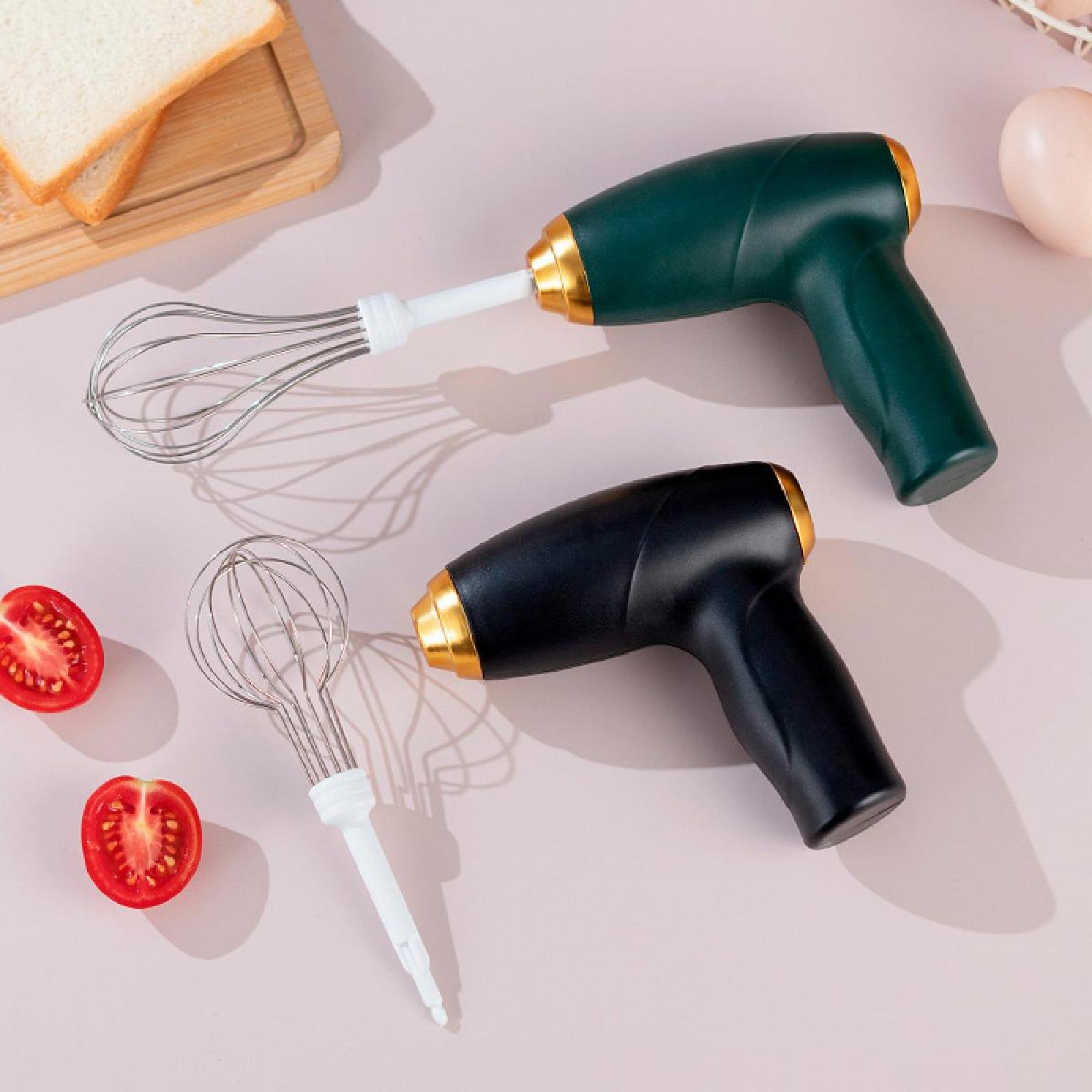 Zwei elektrische Schneebesen, grün und schwarz, liegen mit halbierten Tomaten, Eiern und Brot. Sie haben goldene Akzente.