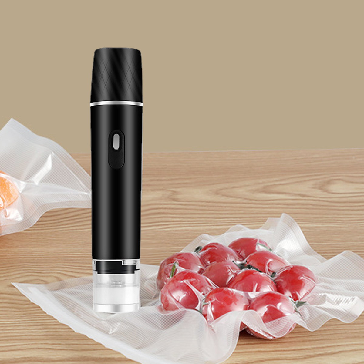Ein schwarzes Vakuumiergerät steht neben Tomaten in einer Klarsichttüte. Orangenfrüchte sind in einer Tüte links. Alles auf Holzoberfläche.