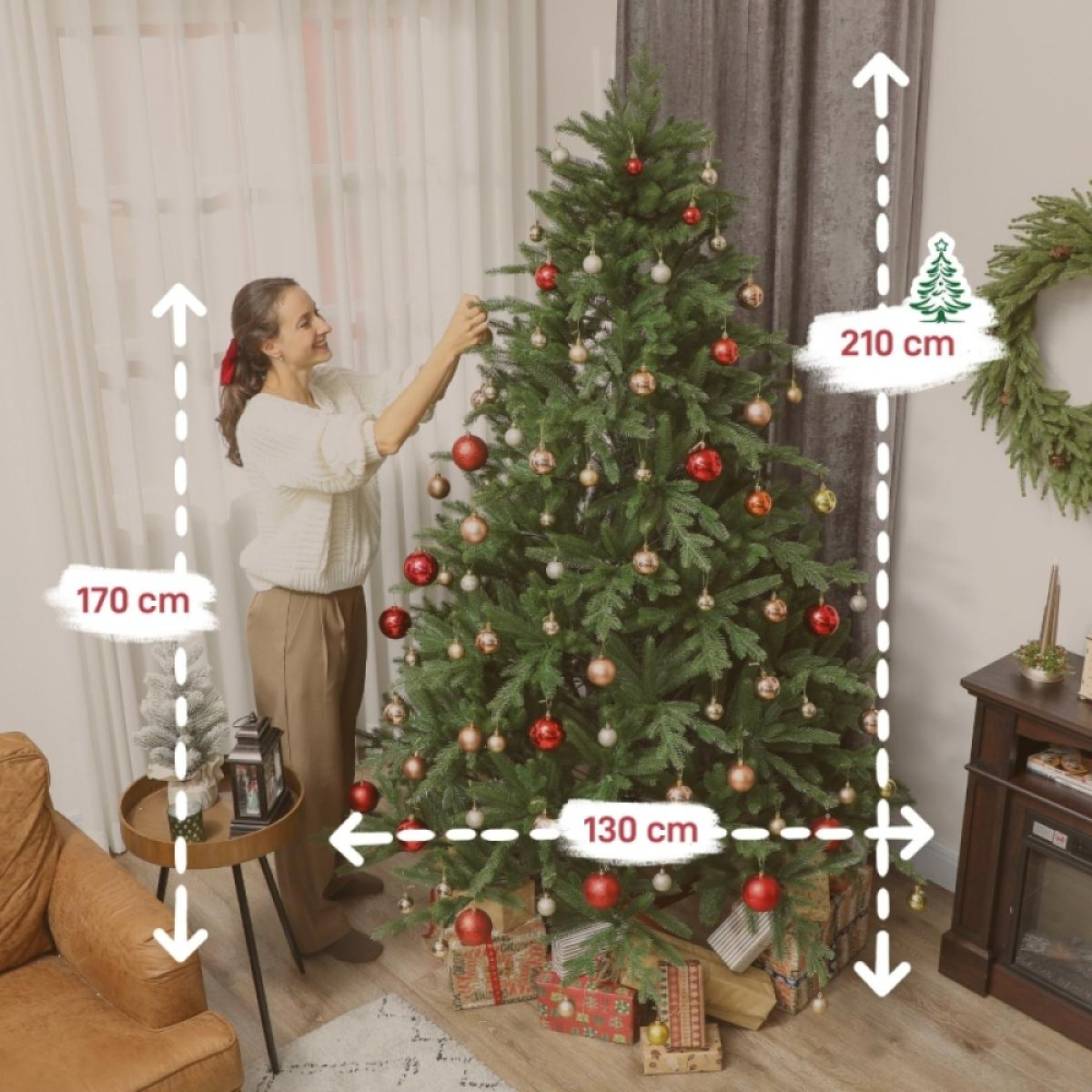 Eine Frau schmückt einen Weihnachtsbaum mit roten und goldenen Ornamenten. Geschenke liegen unter dem Baum. Maße sind angegeben.