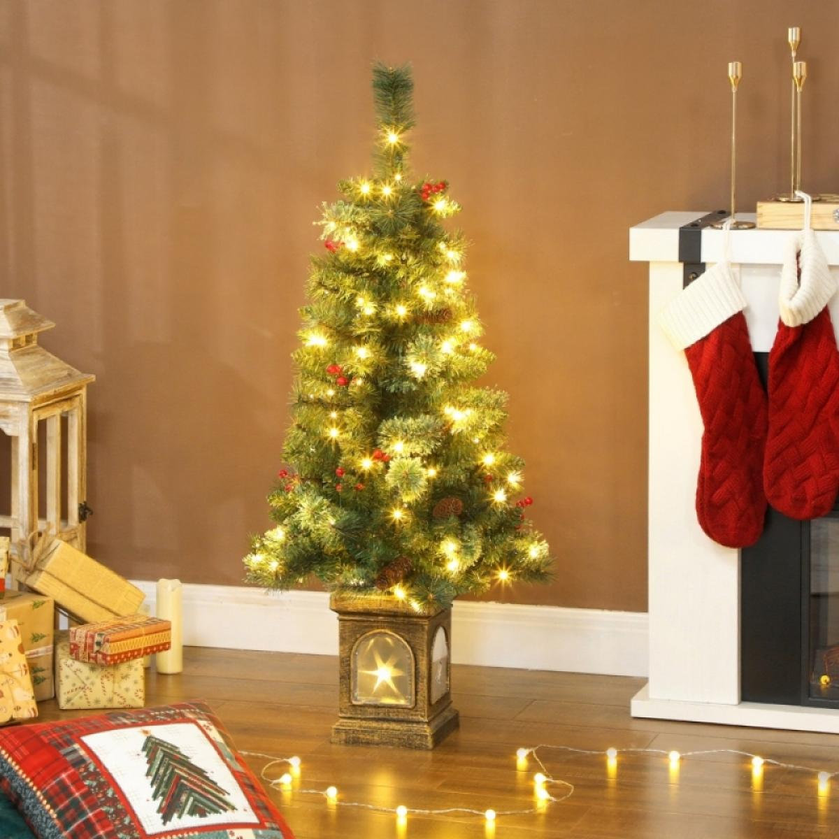 Ein geschmückter Weihnachtsbaum mit Lichtern, roten Beeren und Tannenzapfen. Geschenke, Strümpfe und ein Kamin sind ebenfalls sichtbar.
