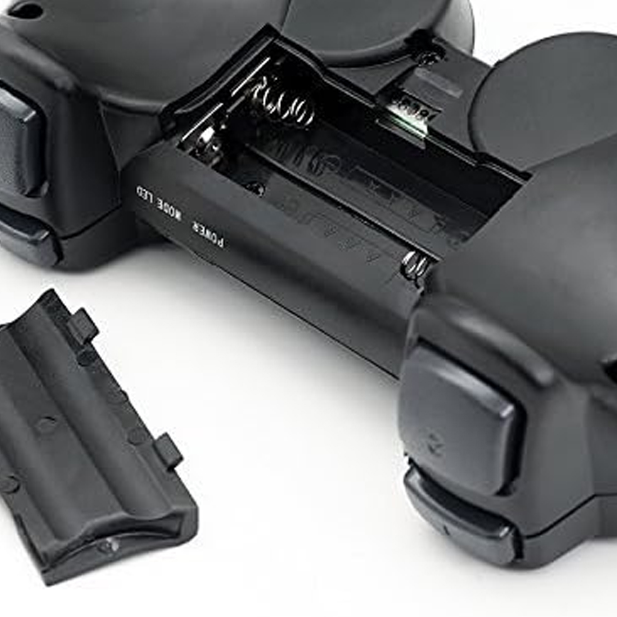 Nahaufnahme eines schwarzen Geräts mit offenem Batteriefach. Die Abdeckung ist abgenommen. Das Gerät hat abgerundete Kanten.
