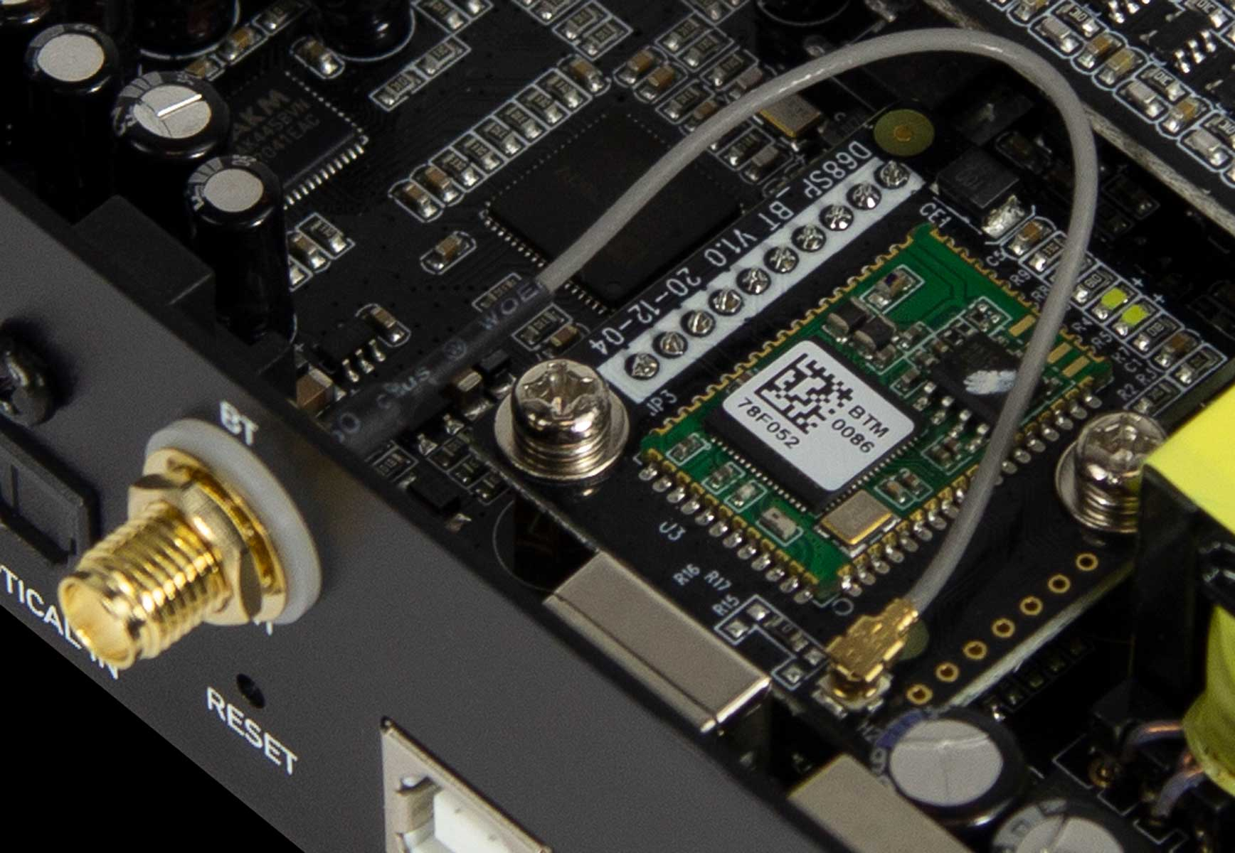 Nahaufnahme einer Leiterplatte. Ein goldener Stecker, ein grünes Bluetooth-Modul und verschiedene elektronische Bauteile sind sichtbar.