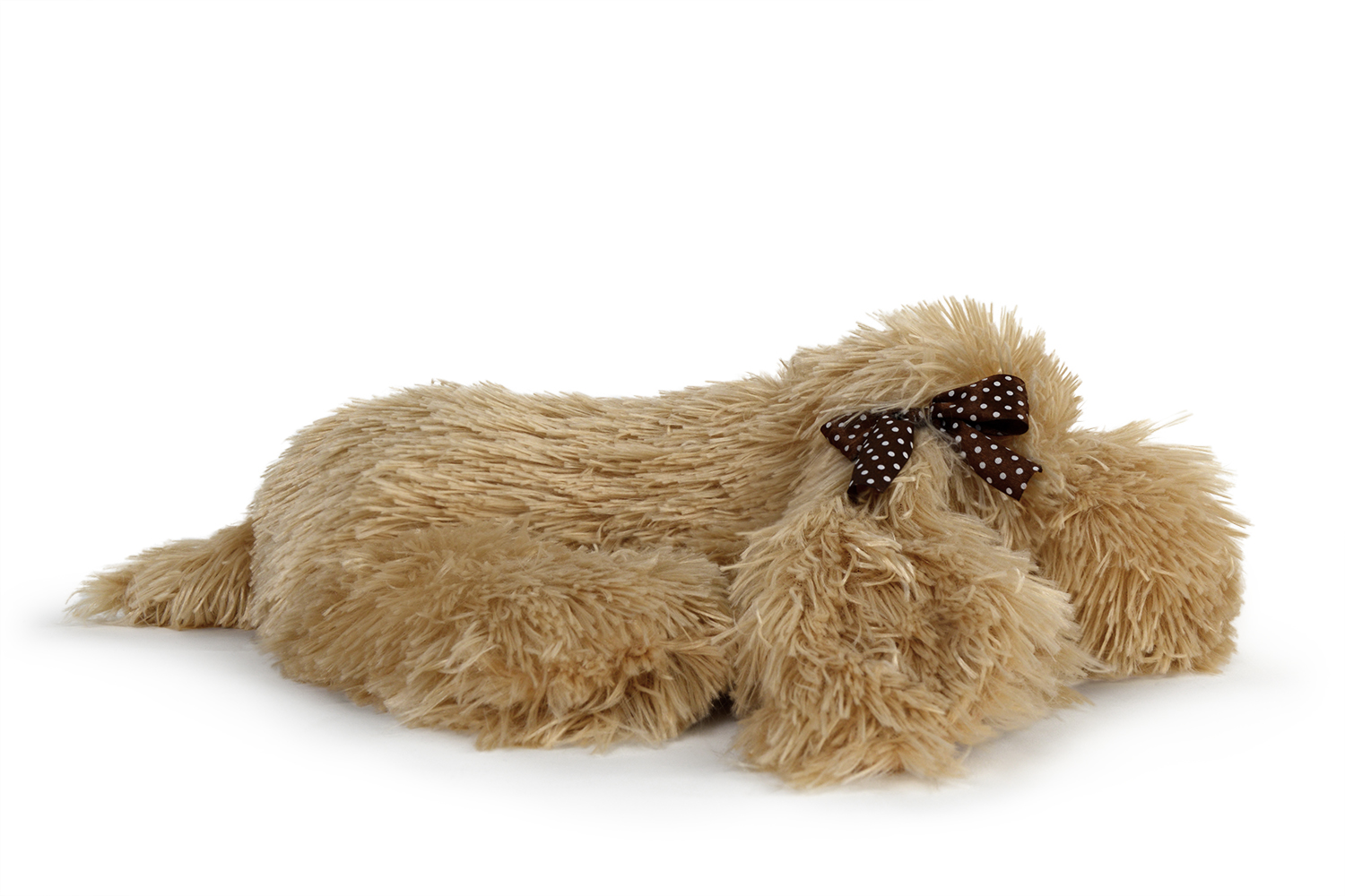 Ein flauschiges beiges Hundespielzeug mit einer braunen Schleife. Das Spielzeug liegt auf einer weißen Oberfläche.