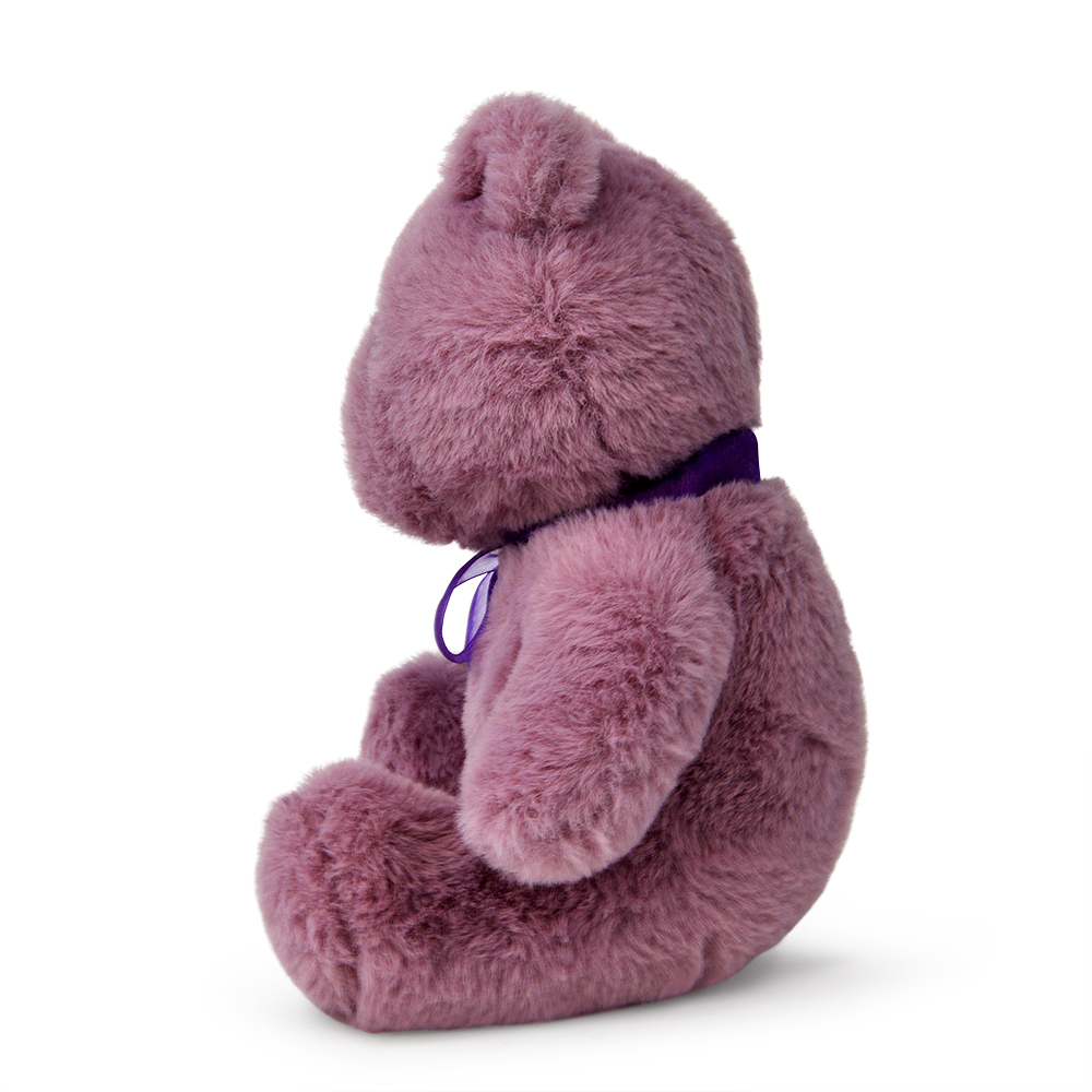 Ein rosa Teddybär sitzt nach links gerichtet und trägt ein lila Band um den Hals. Der Bär befindet sich auf weißem Hintergrund.