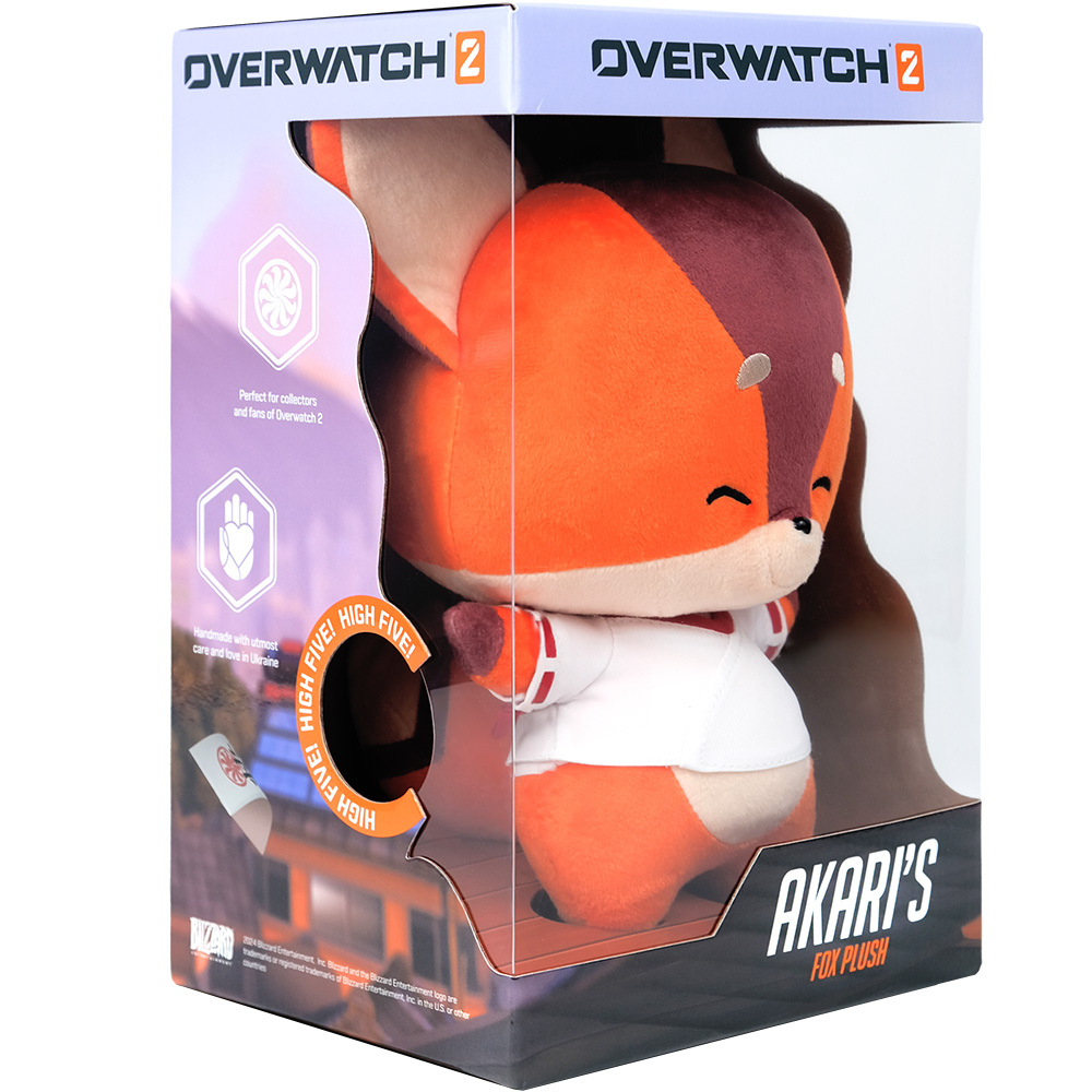 Ein Plüschtier eines Fuchscharakters aus Overwatch 2 in einer durchsichtigen Displaybox. Der Fuchs ist orange und weiß und hat ein lächelndes Gesicht.
