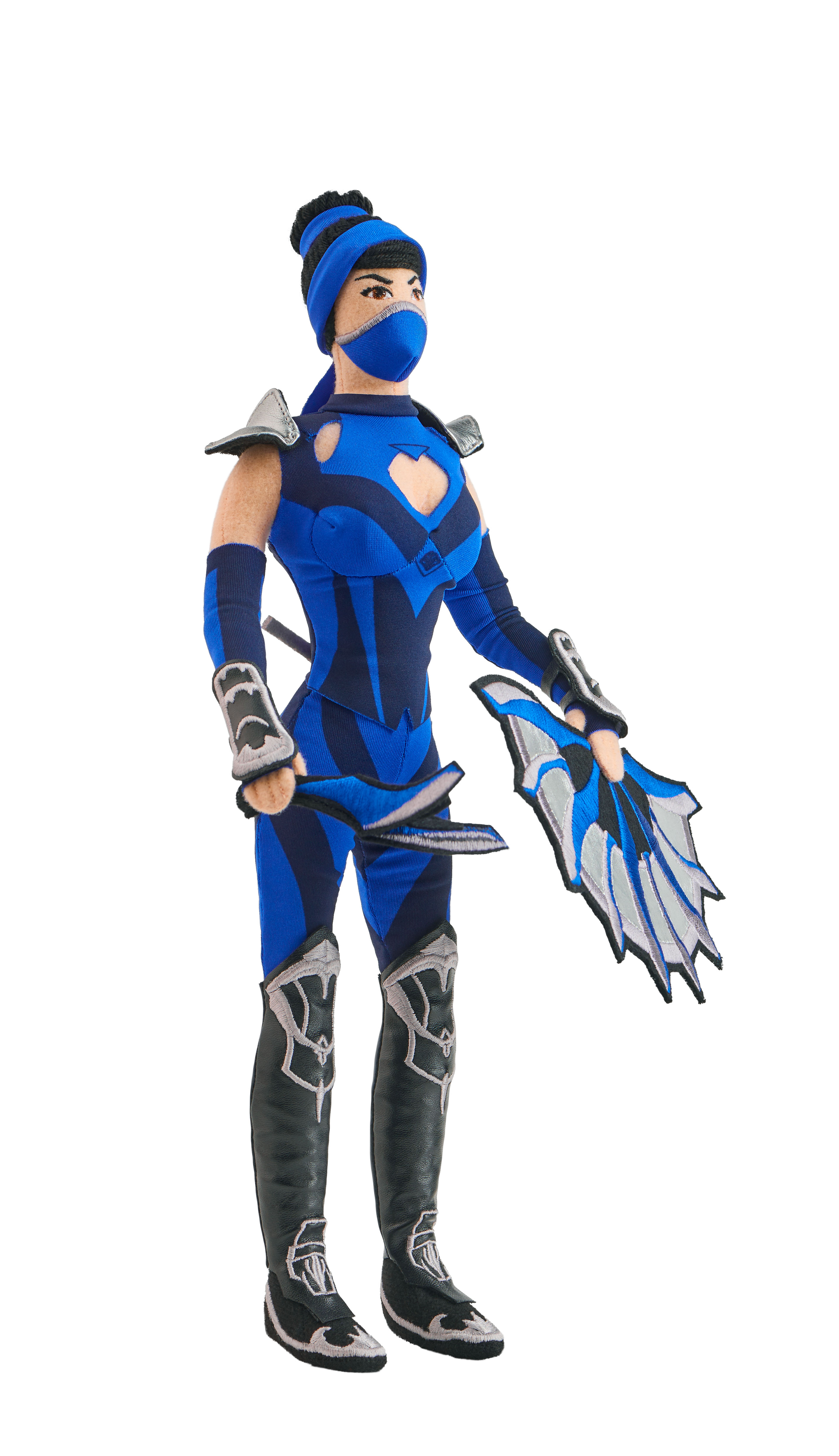 Eine Puppe einer weiblichen Figur in blau-schwarzer Ninja-Kleidung, mit Maske und Waffen, vor weißem Hintergrund.