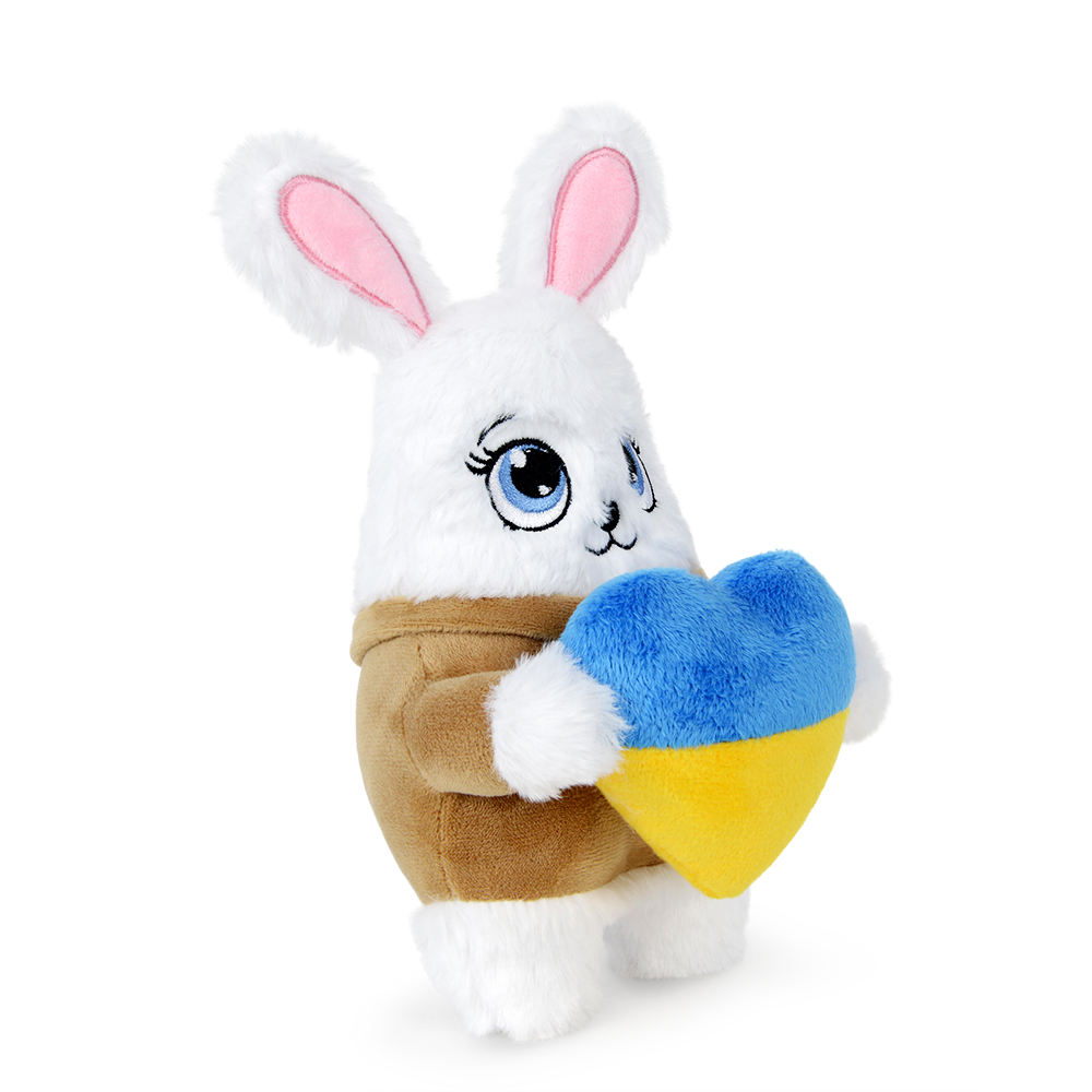 Ein weißes Plüschkaninchen hält ein Herz in den Farben der ukrainischen Flagge. Das Kaninchen trägt eine braune Jacke.