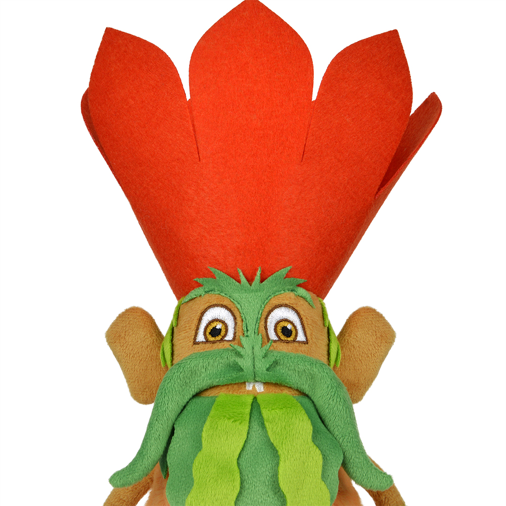 Ein Plüschtier mit einem orangefarbenen blütenartigen Hut. Es hat einen grünen Bart und Augenbrauen, braune Ohren und ein Gesicht und große gelbe Augen.