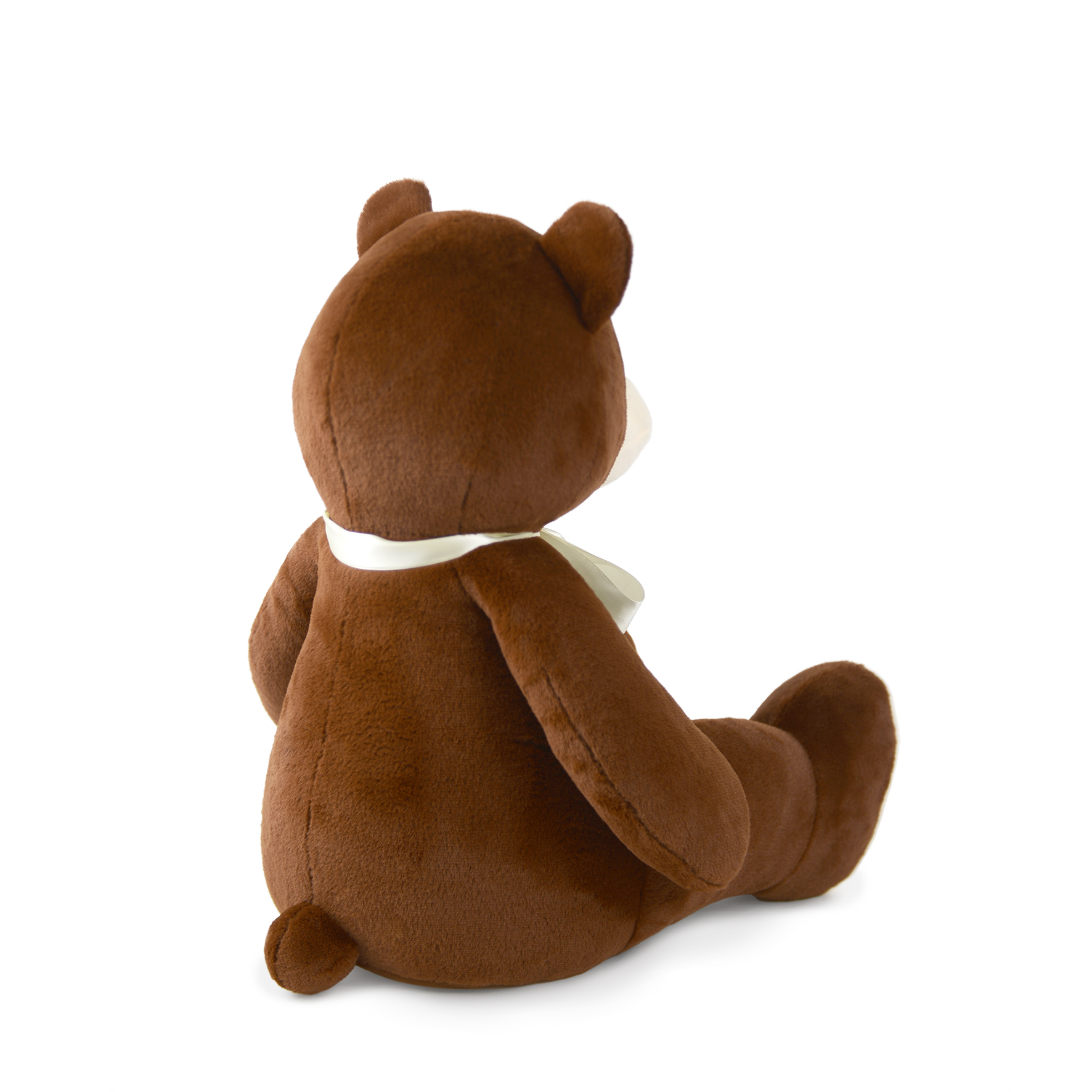Ein brauner Teddybär sitzt abgewandt. Er hat einen weißen Schal und befindet sich auf weißem Hintergrund. Das Fell ist weich.