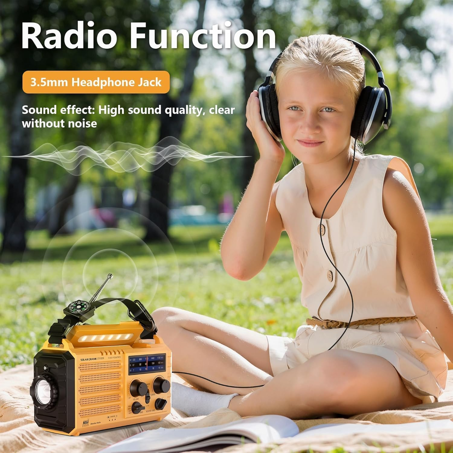 Dziewczyna ze słuchawkami słucha radia. Żółte radio leży na kocu. Scena rozgrywa się na świeżym powietrzu z zieloną trawą.