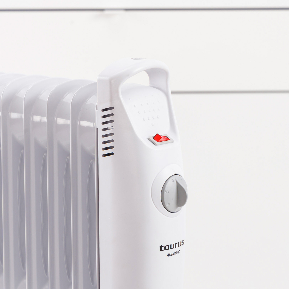 Biały grzejnik olejowy z uchwytem, czerwonym włącznikiem i pokrętłem. Widoczna marka 'Taurus'.