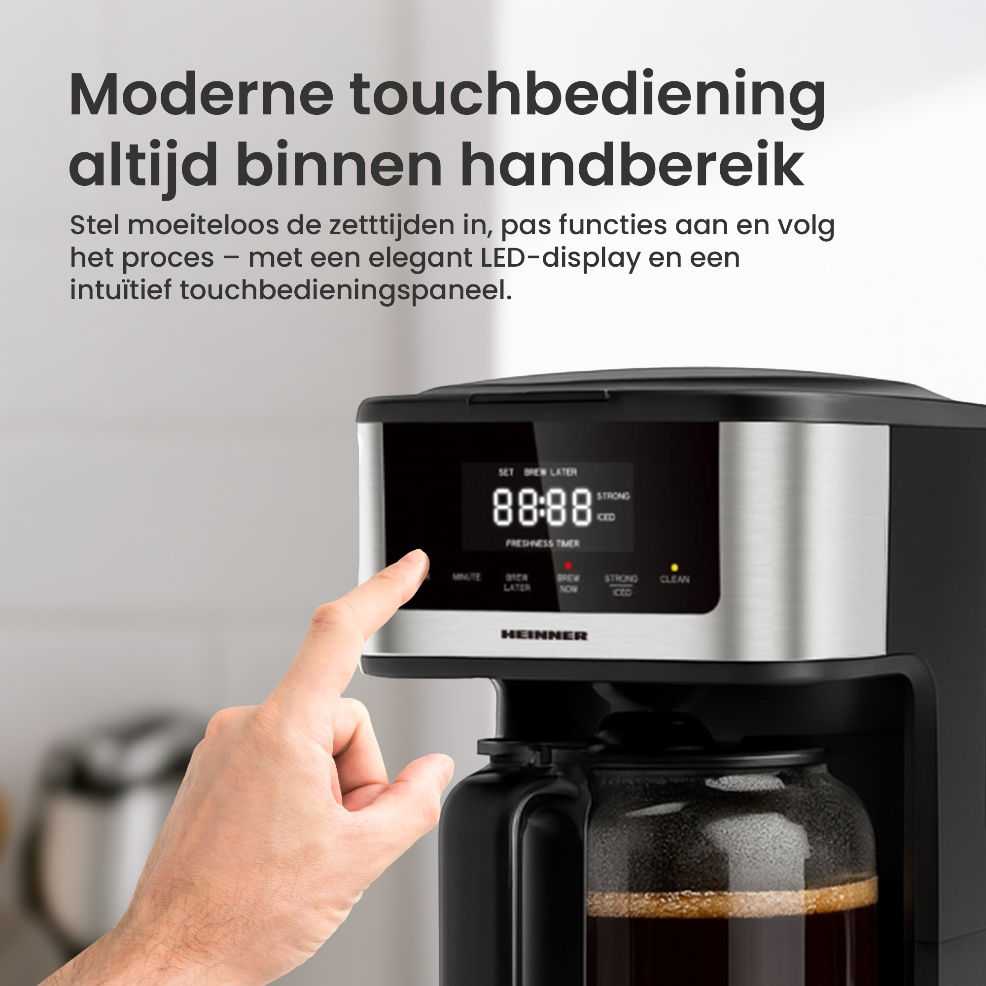 Eine Hand berührt den Bildschirm einer Kaffeemaschine. Die Maschine ist schwarz und silber, mit einer Glaskaraffe.