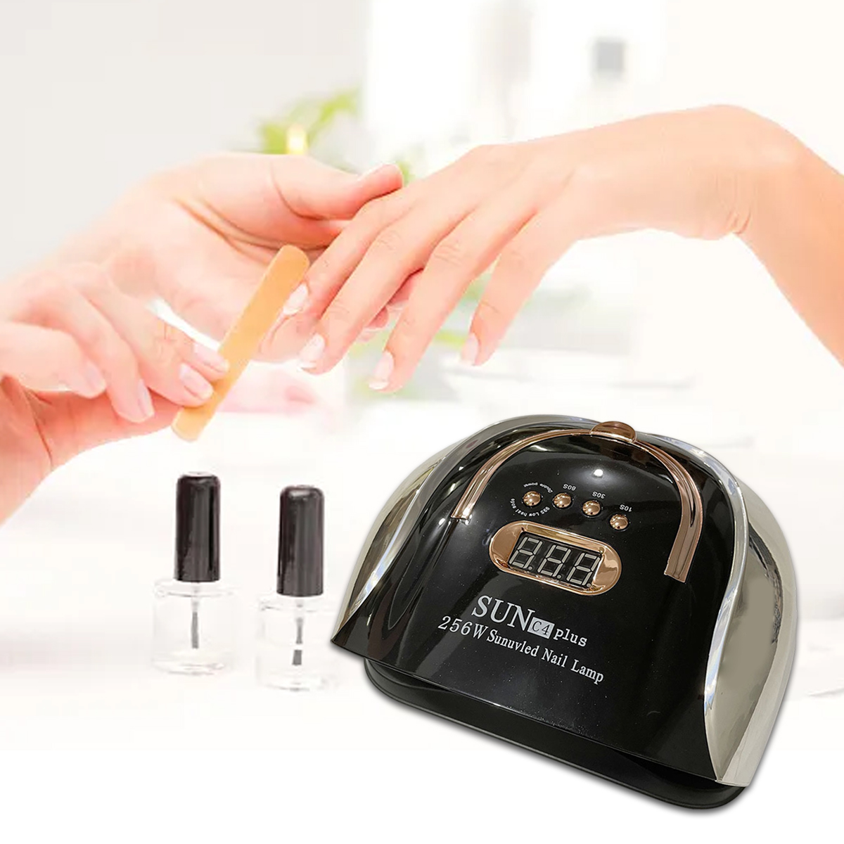 Eine Nagellampe, Nagellackflaschen und Hände sind zu sehen. Eine Hand feilt die Nägel der anderen. Die Lampe hat eine Digitalanzeige.