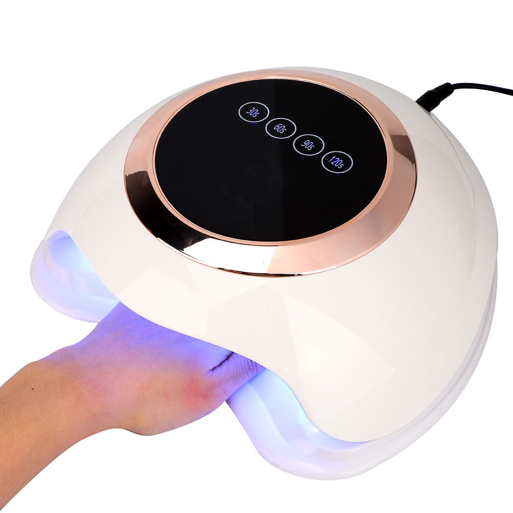 Eine weiße Nagellampe mit einer Hand darin. Die Lampe hat ein Digitaldisplay und Knöpfe. Die Hand ist unter blauem Licht.