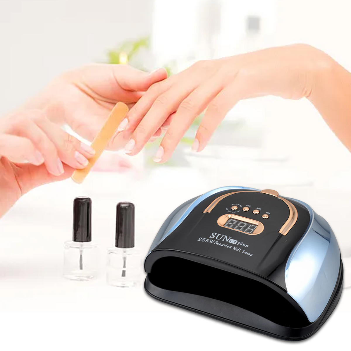 Eine Person feilt Nägel. Eine Nagellampe und zwei Flaschen Politur stehen auf dem Tisch. Die Lampe ist schwarz und gold.